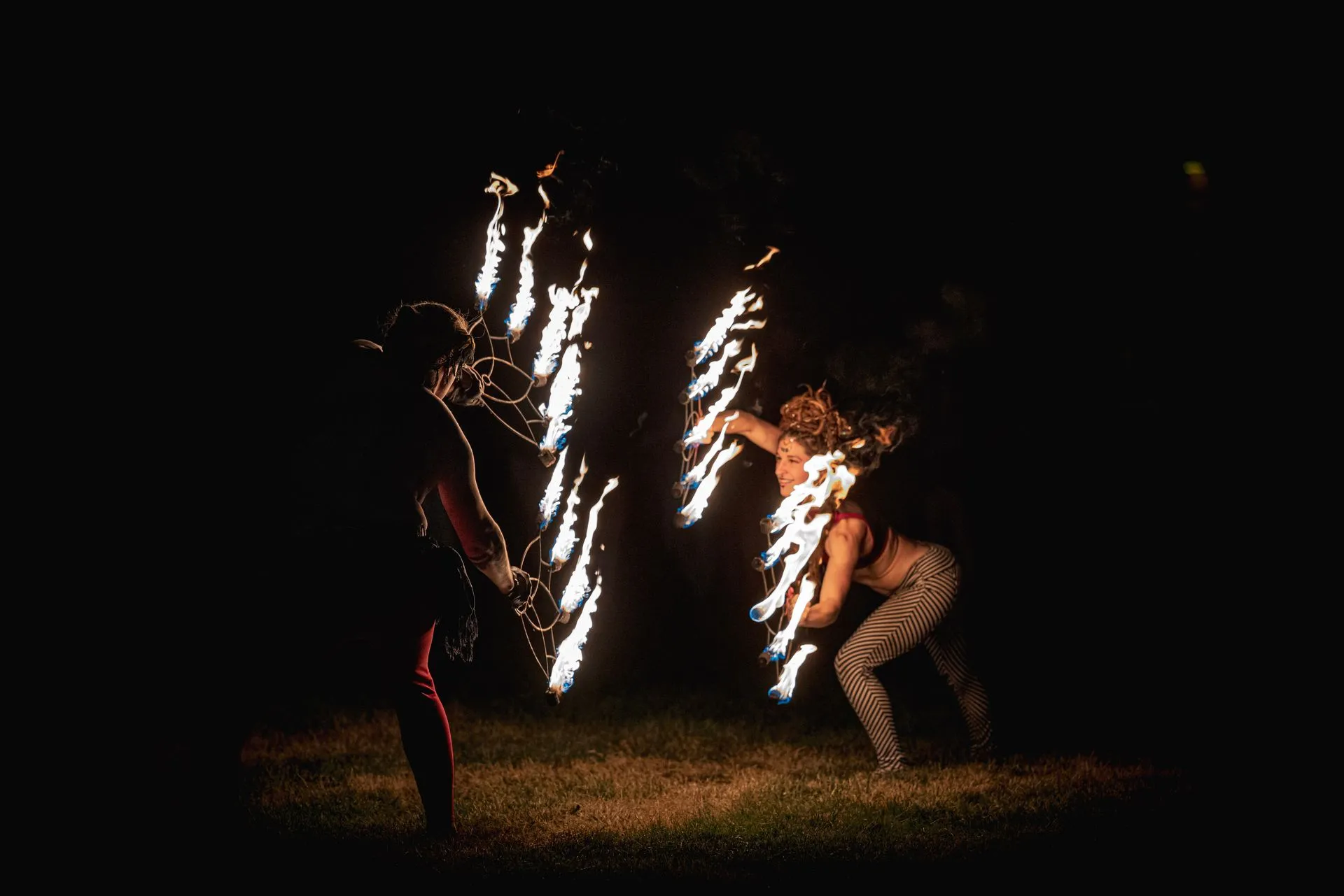 A man and a woman are playing with fire at night.
