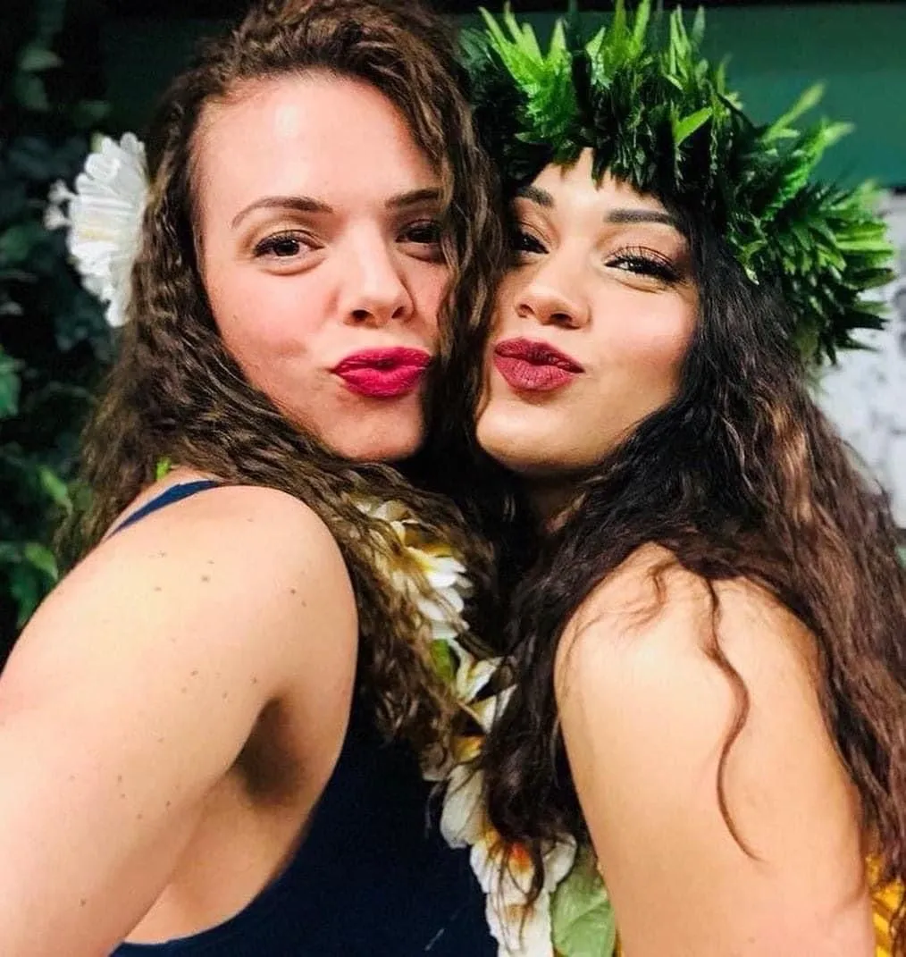 Two women are posing for a picture and one has a flower crown on her head.