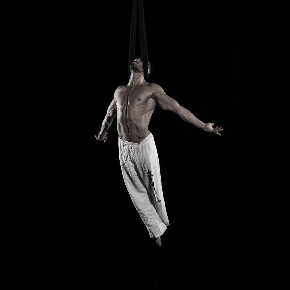A man is hanging upside down in the air with his arms outstretched.