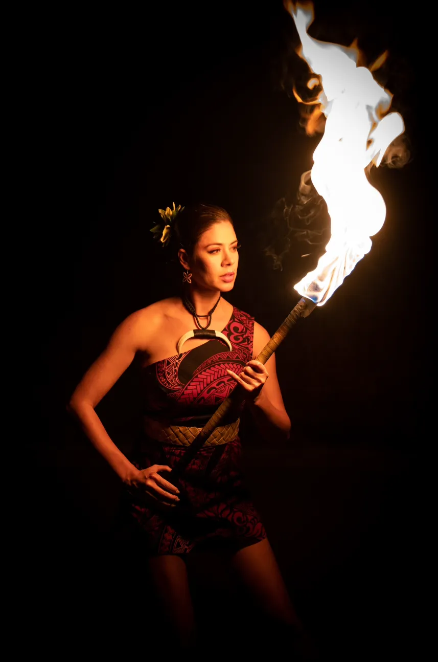 A woman in a red dress is holding a torch in the dark.