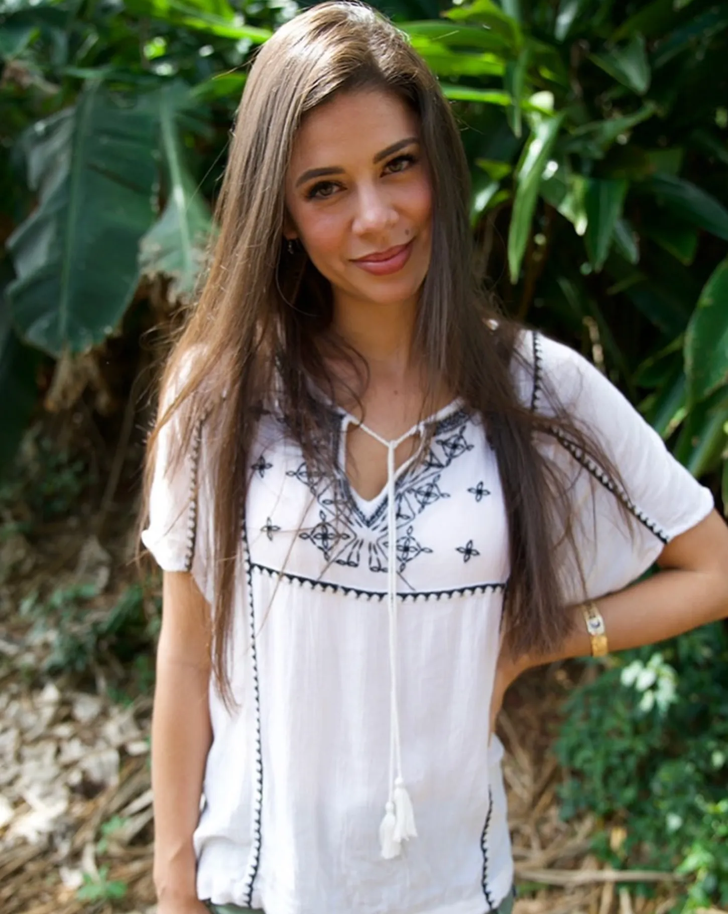A woman is wearing a white top with black embroidery