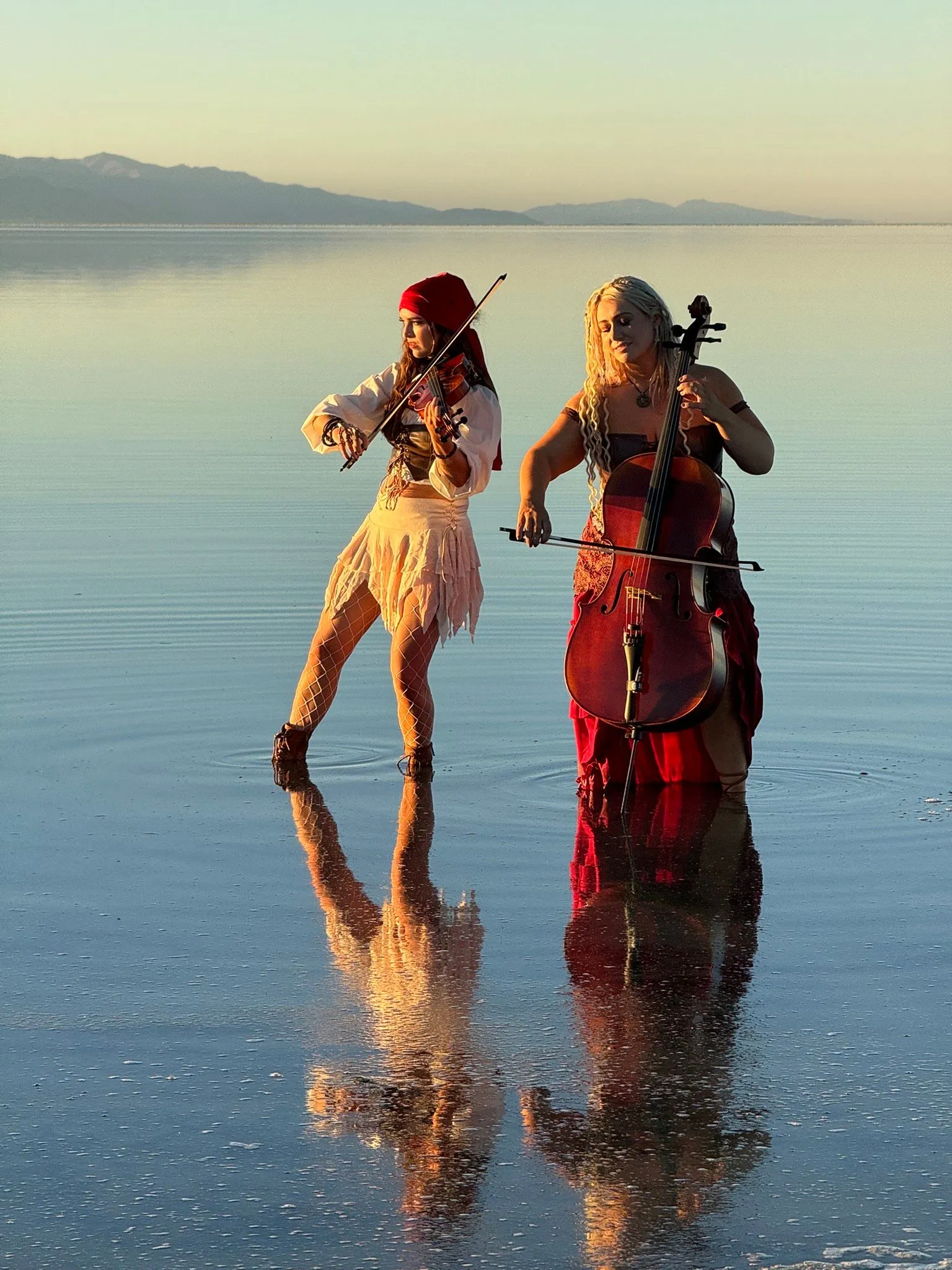 Two women playing violins and cello in the water