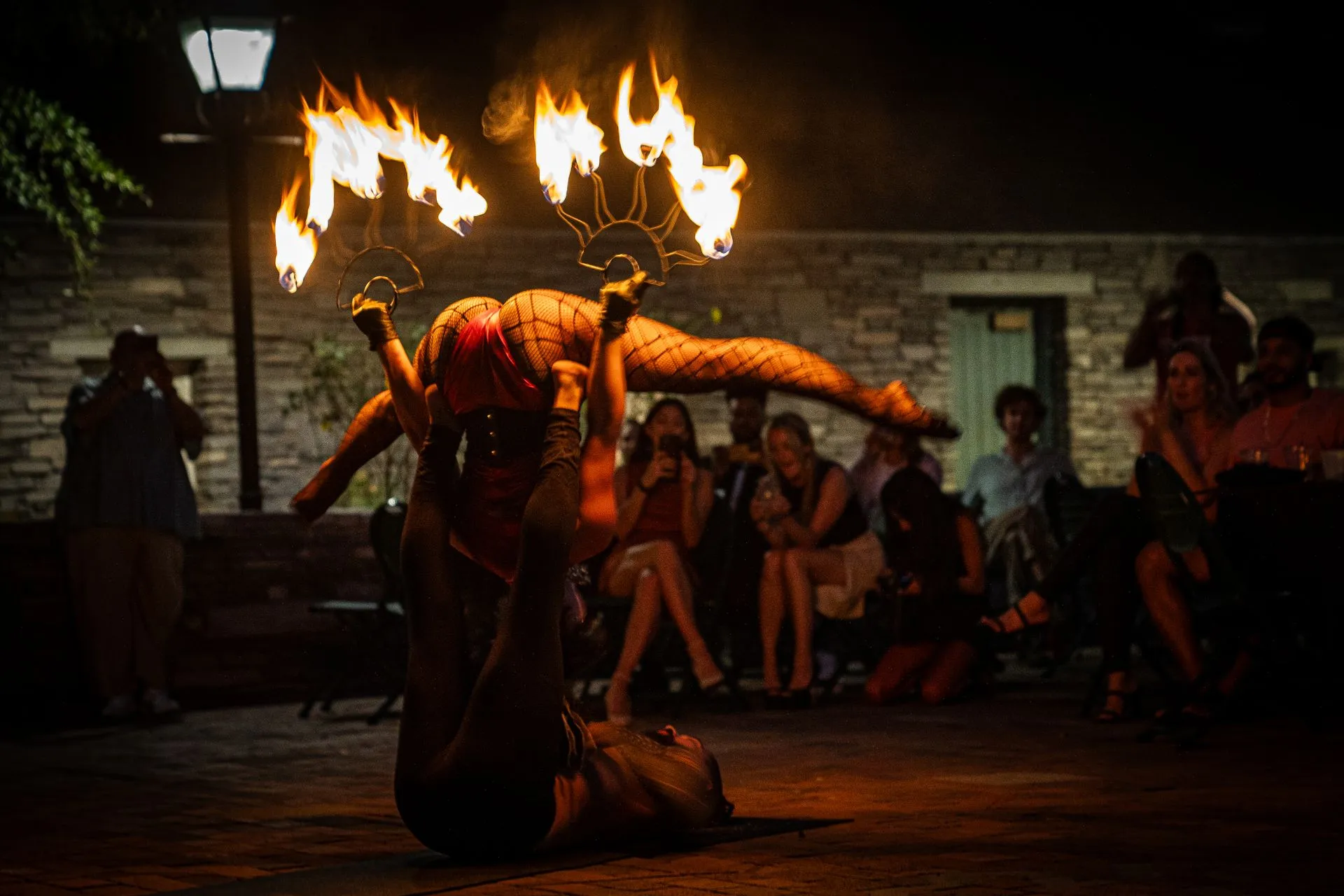 A woman is doing a fire performance in front of a crowd of people.