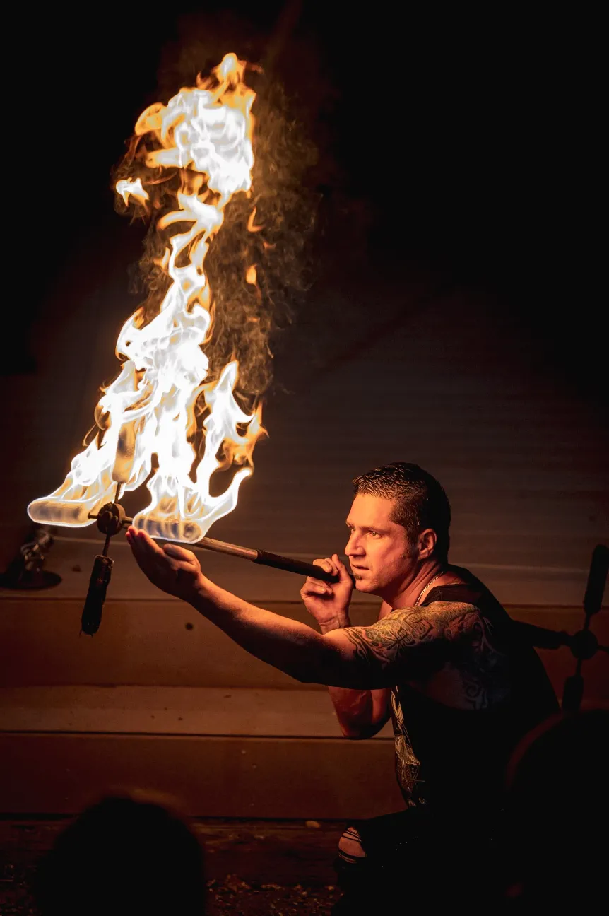 A man is holding a stick with flames coming out of it.