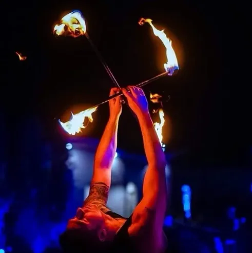 A man is juggling fire sticks in the dark
