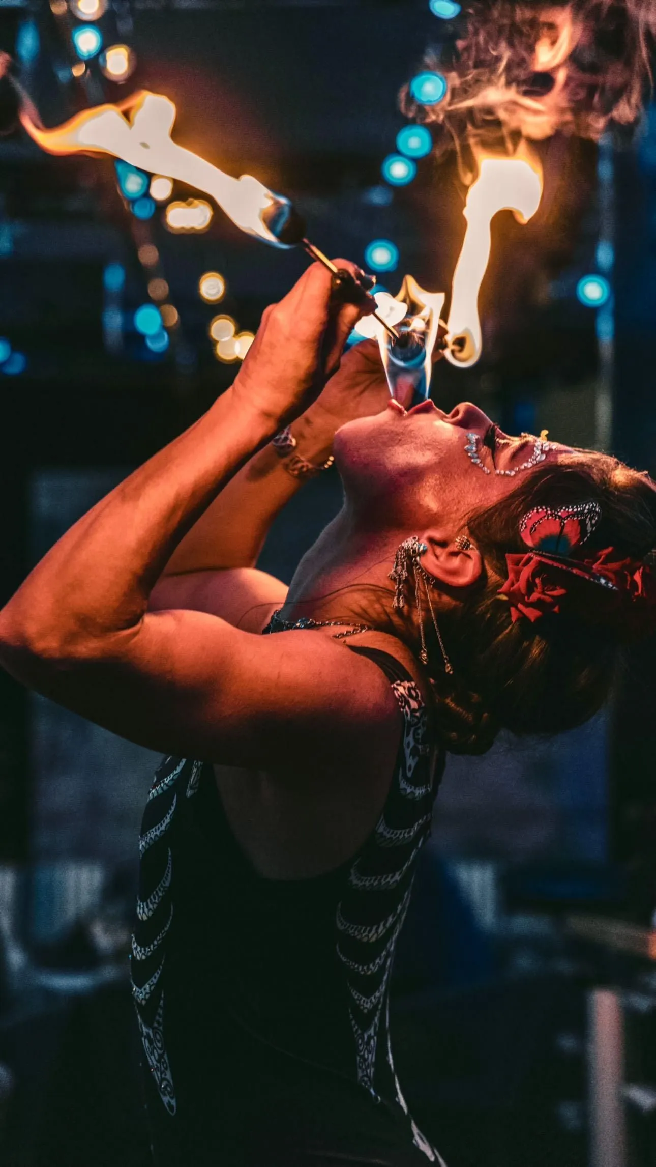 A woman is blowing fire into her mouth.
