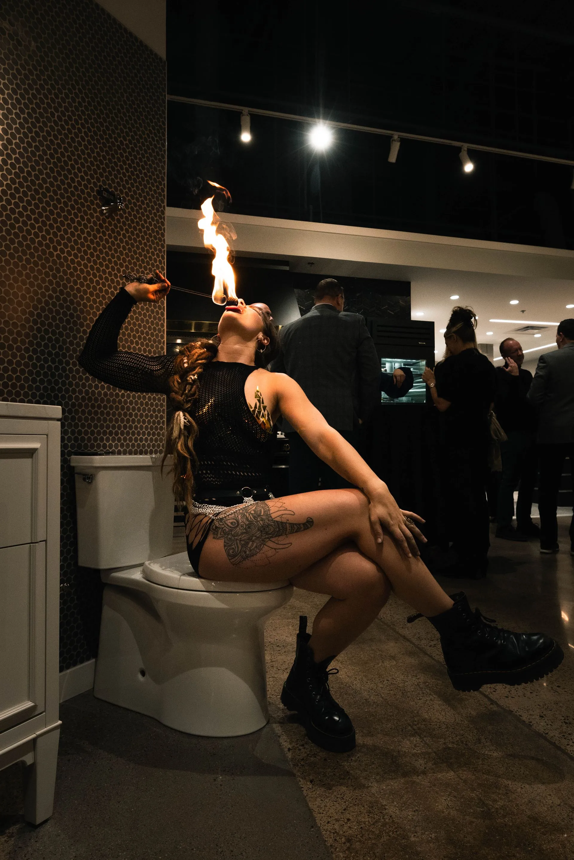 A woman is sitting on a toilet with a fireball in her mouth.