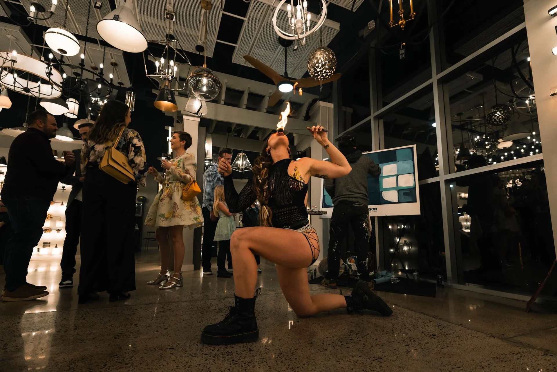 A woman is juggling fire in a room with people.