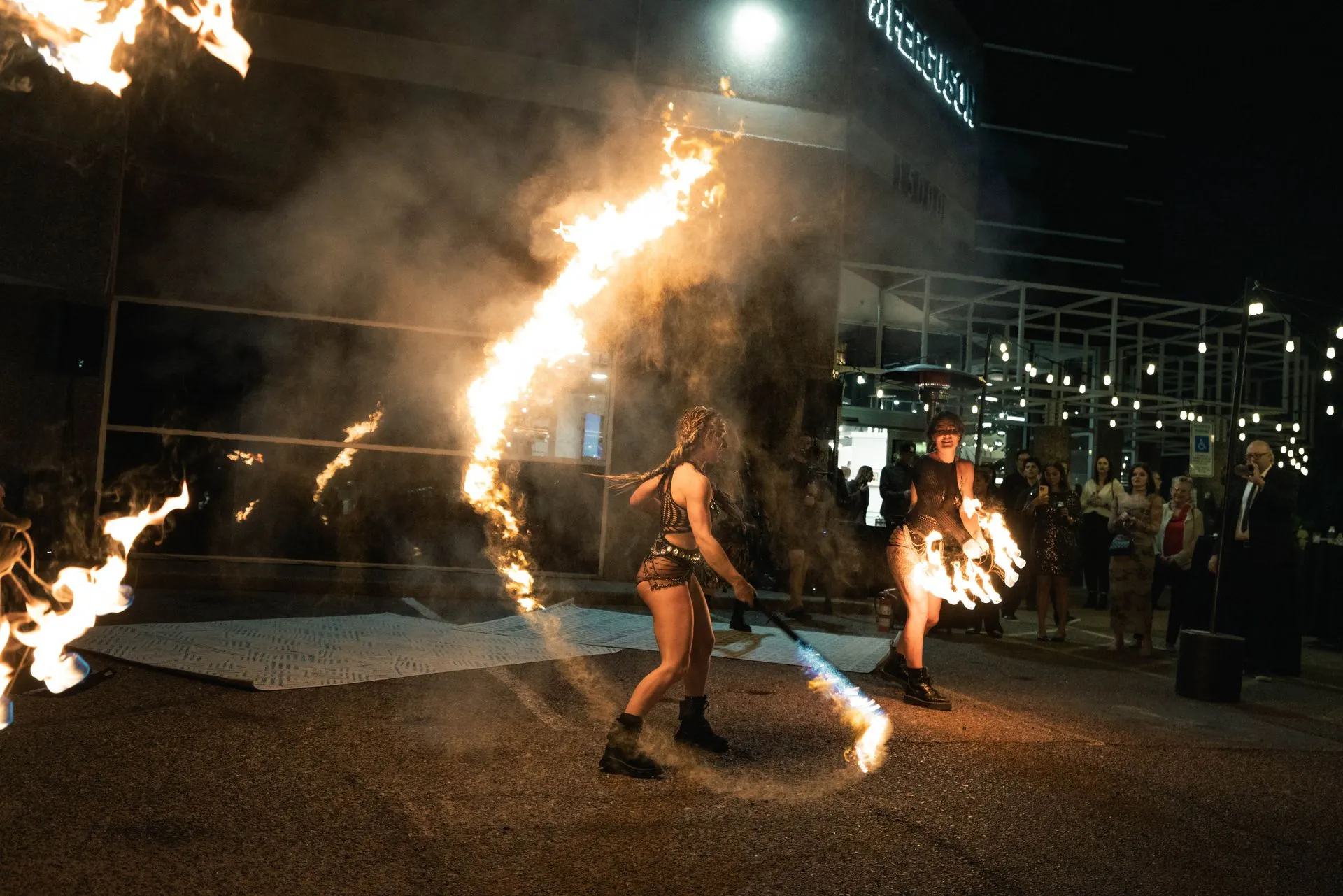 A group of people are playing with fire in front of a building at night.