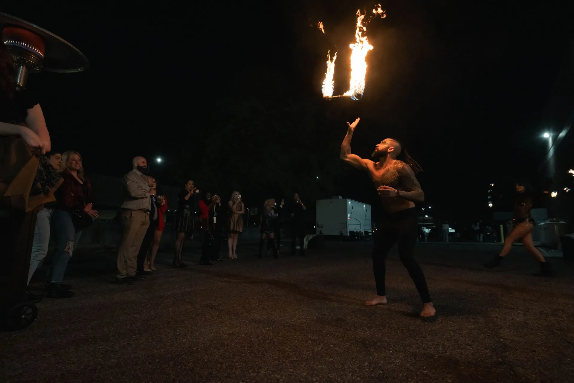 A man is throwing a fireball in the air at night.