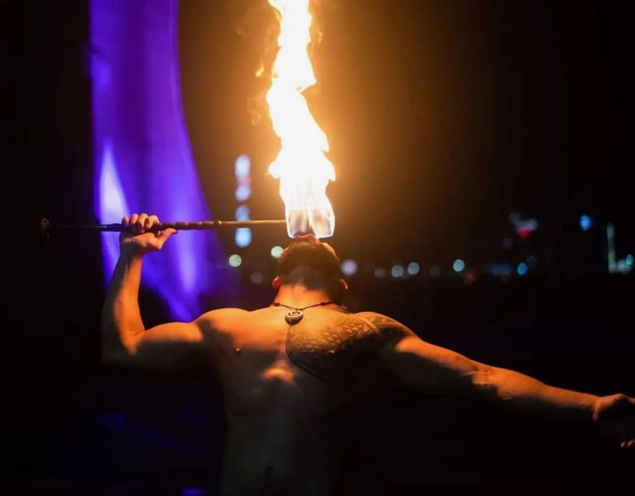 A man is holding a stick with flames coming out of it.
