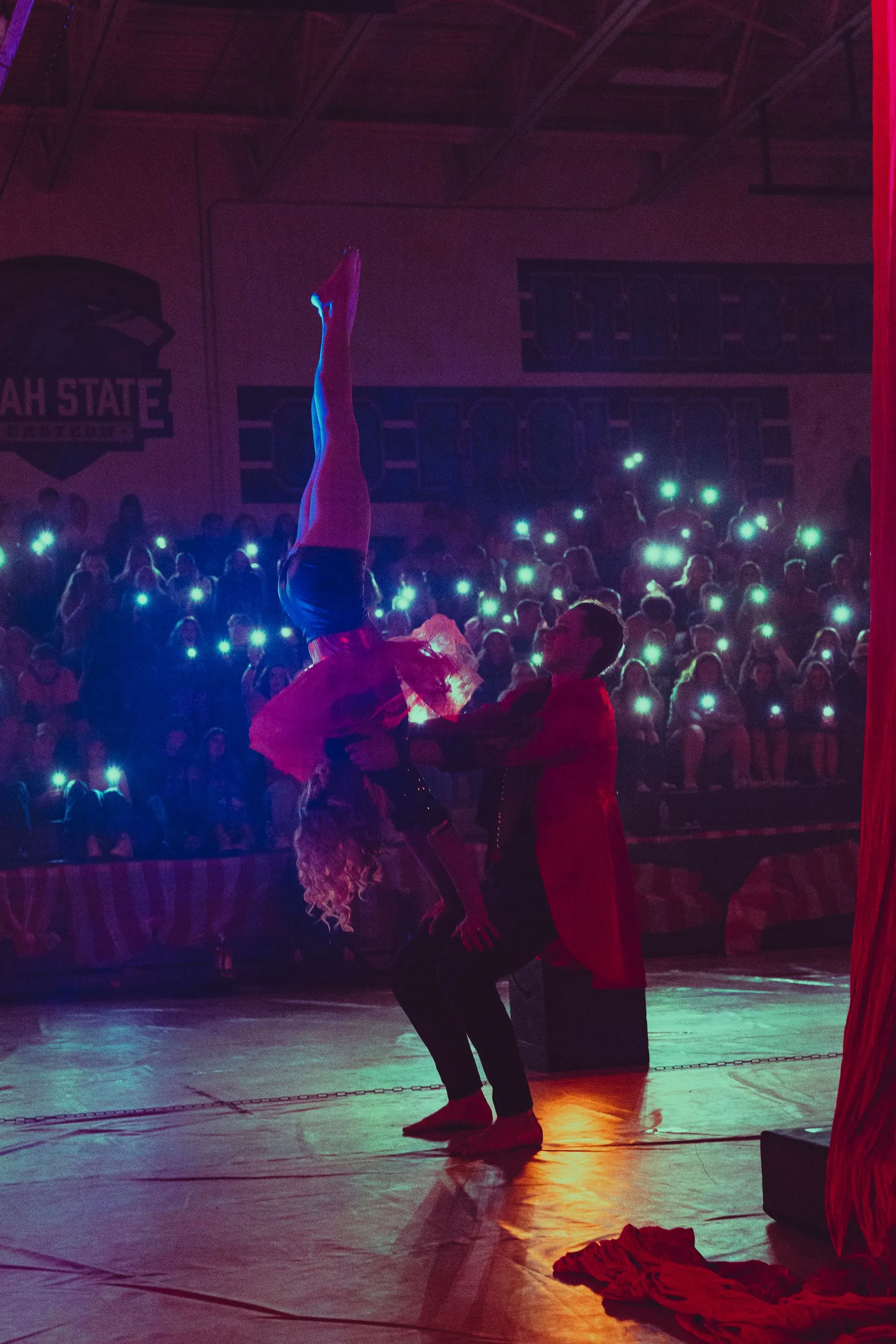 A couple of people are dancing on a stage in front of a crowd.