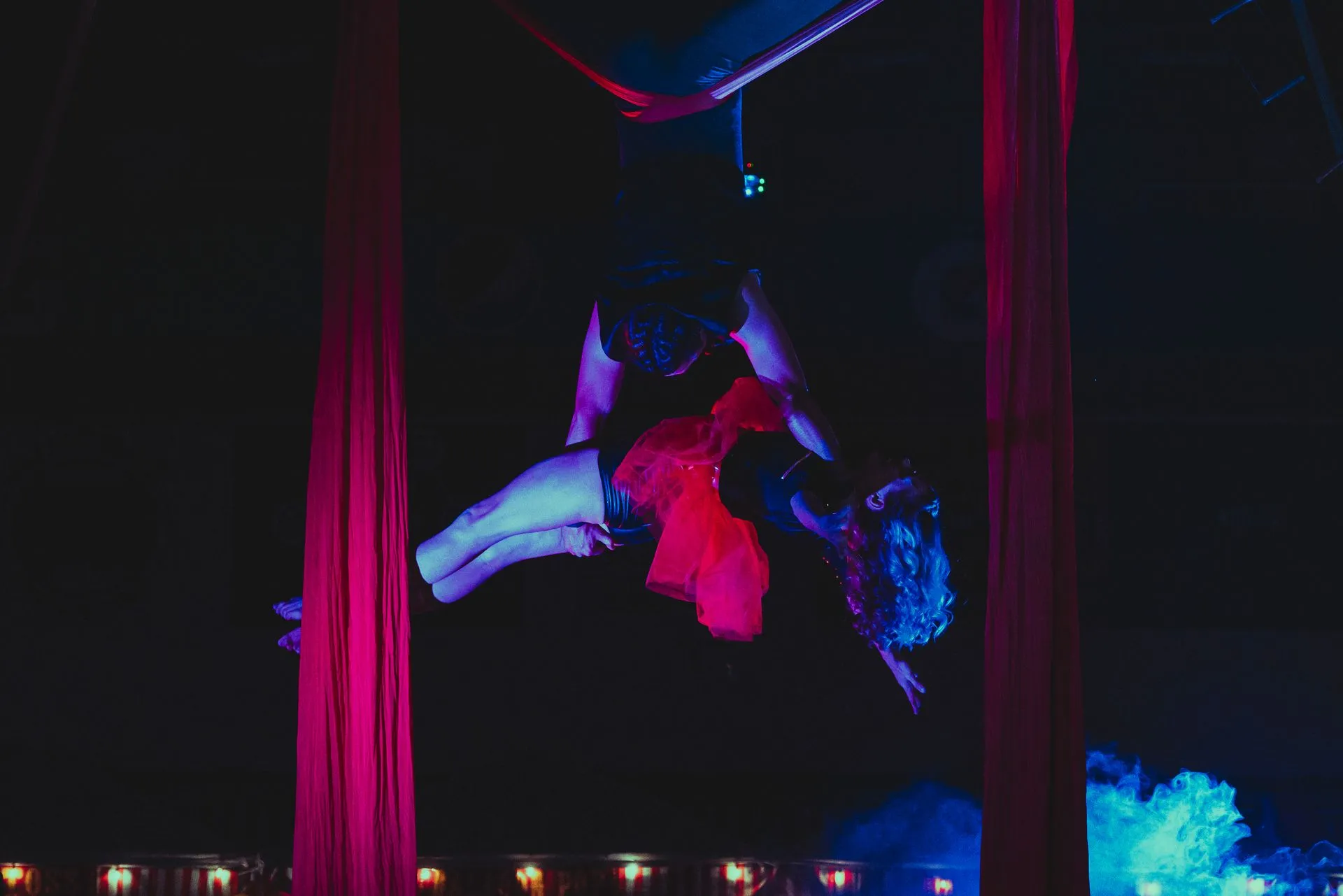 A woman is performing aerial acrobatics in a dark room.