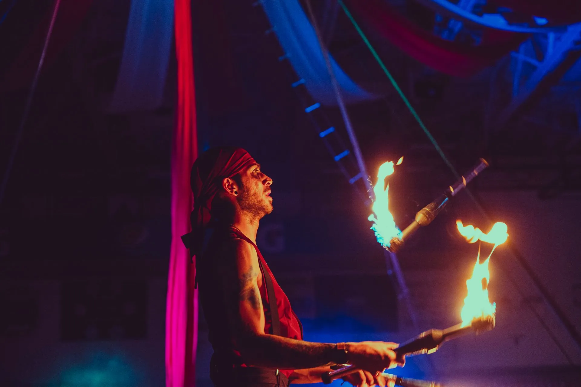 A man is juggling fire in a dark room.