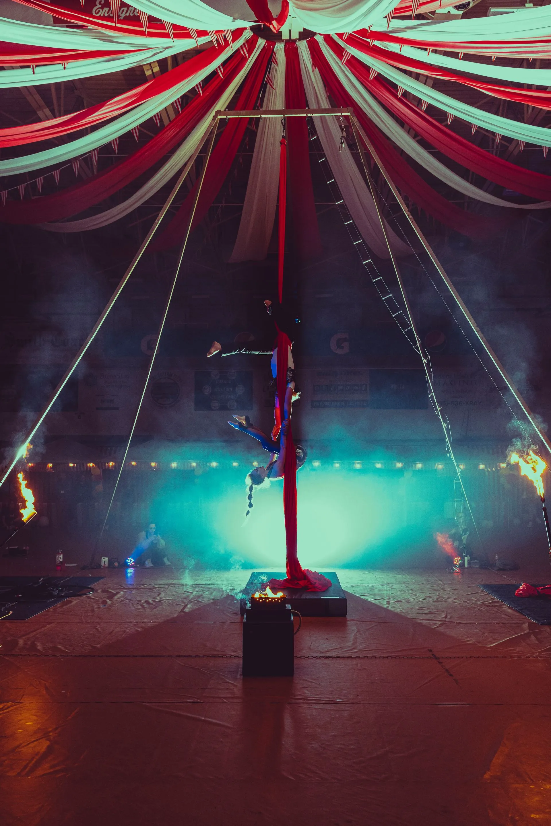 A person is doing aerial acrobatics in a circus tent.