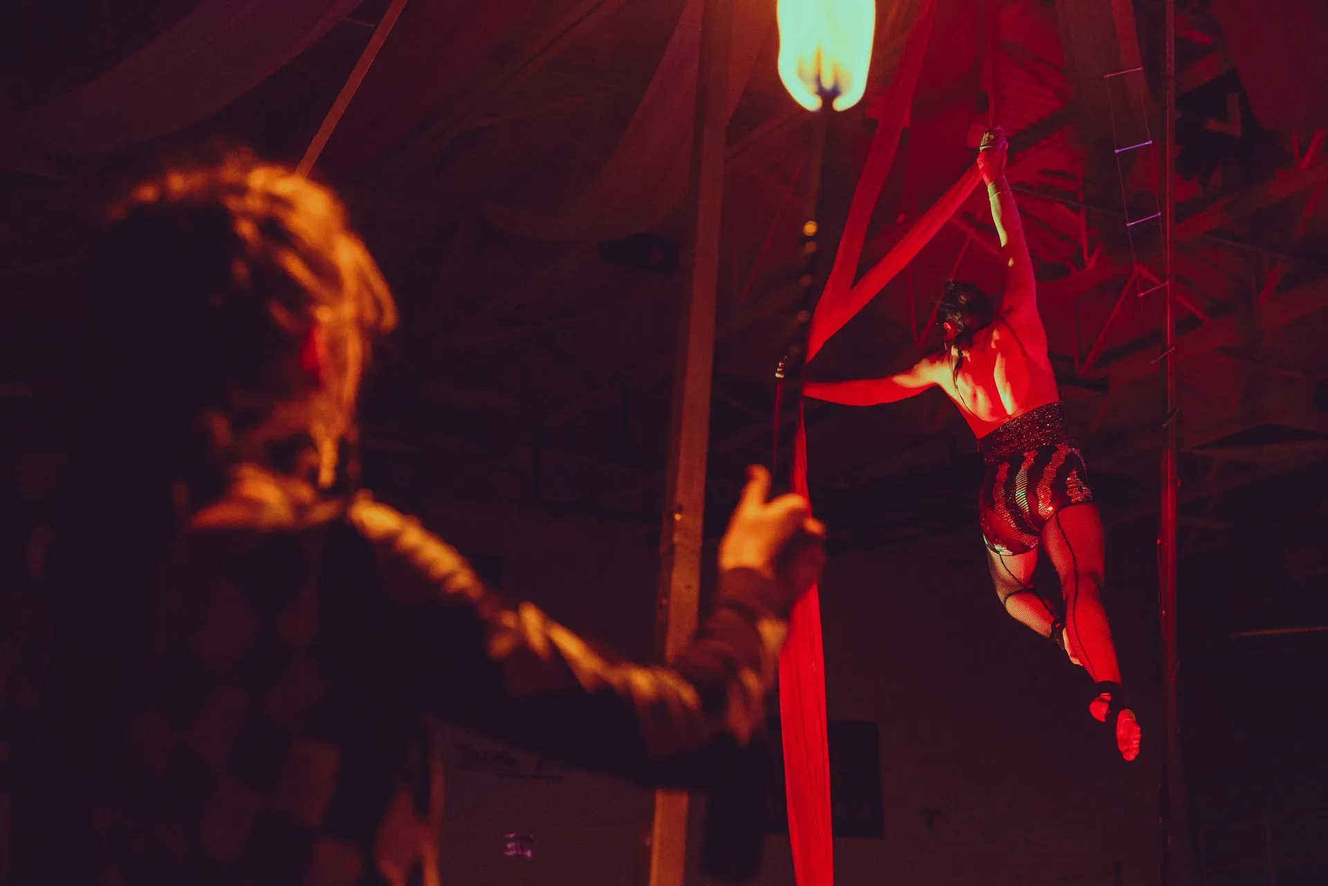 A man is taking a picture of a woman performing aerial acrobatics.