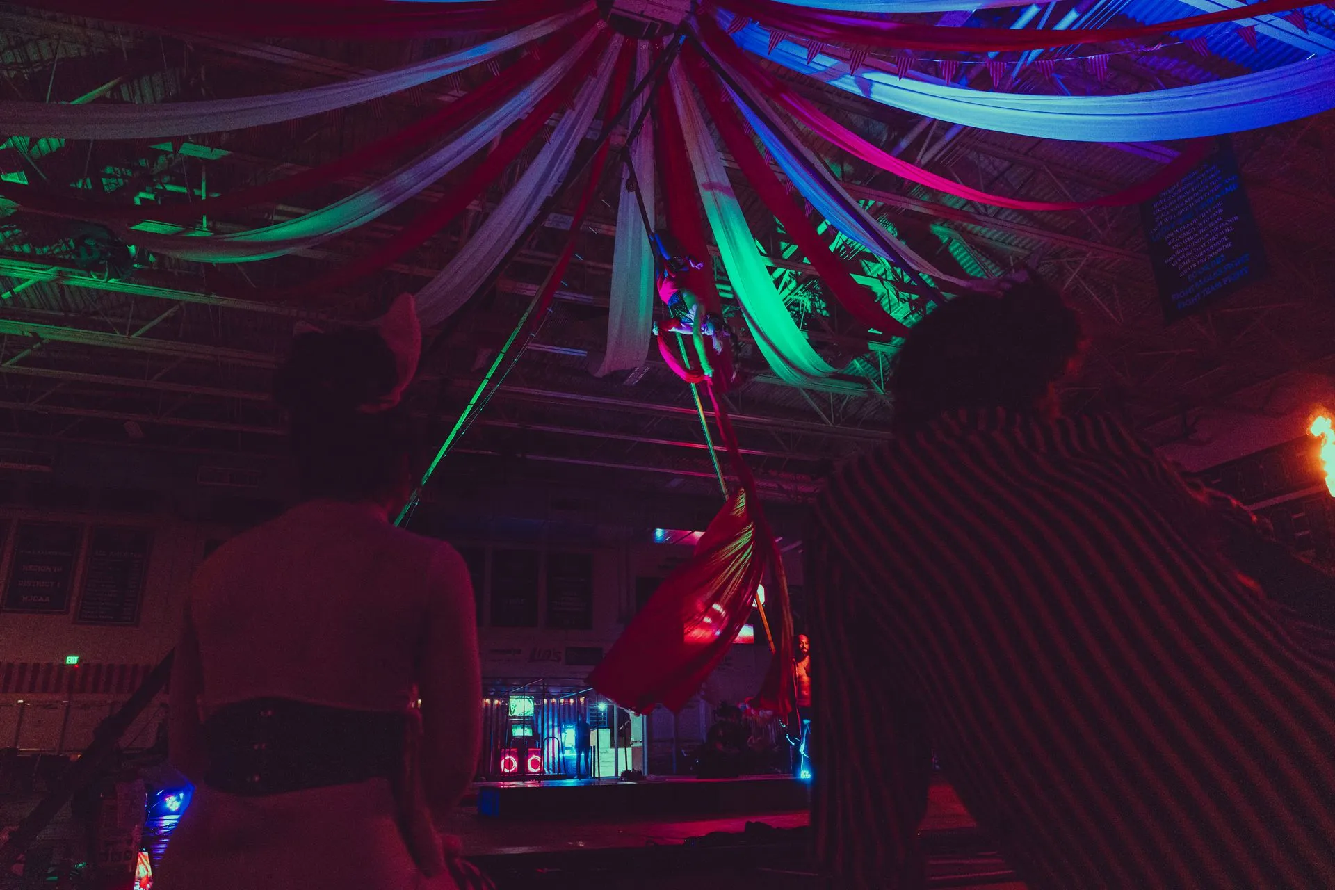 A group of people are dancing in a dark room with colorful lights.