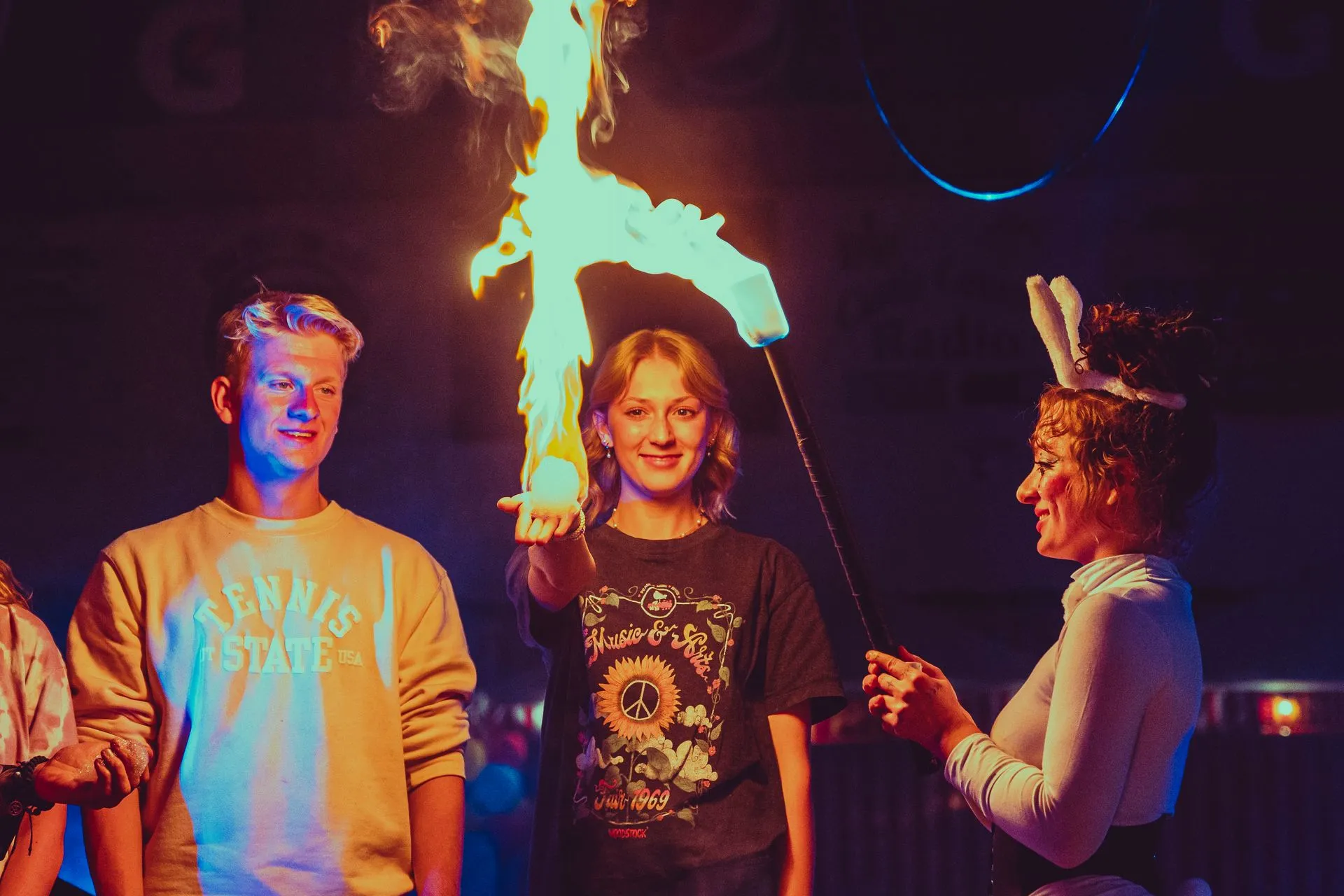 A group of people are standing in front of a fire.