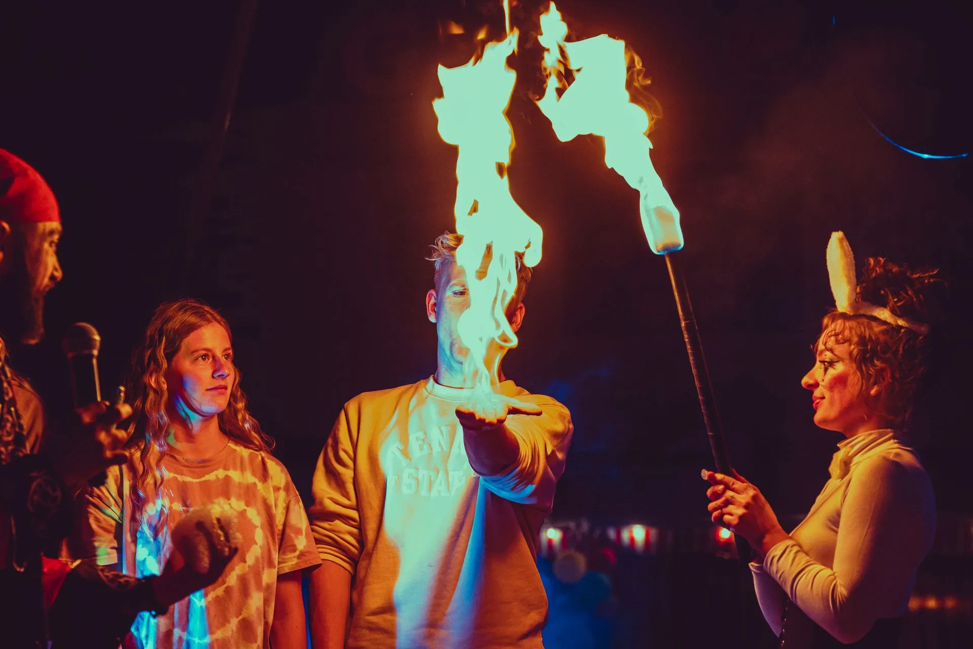 A group of people are standing around a man holding a torch in his hand.
