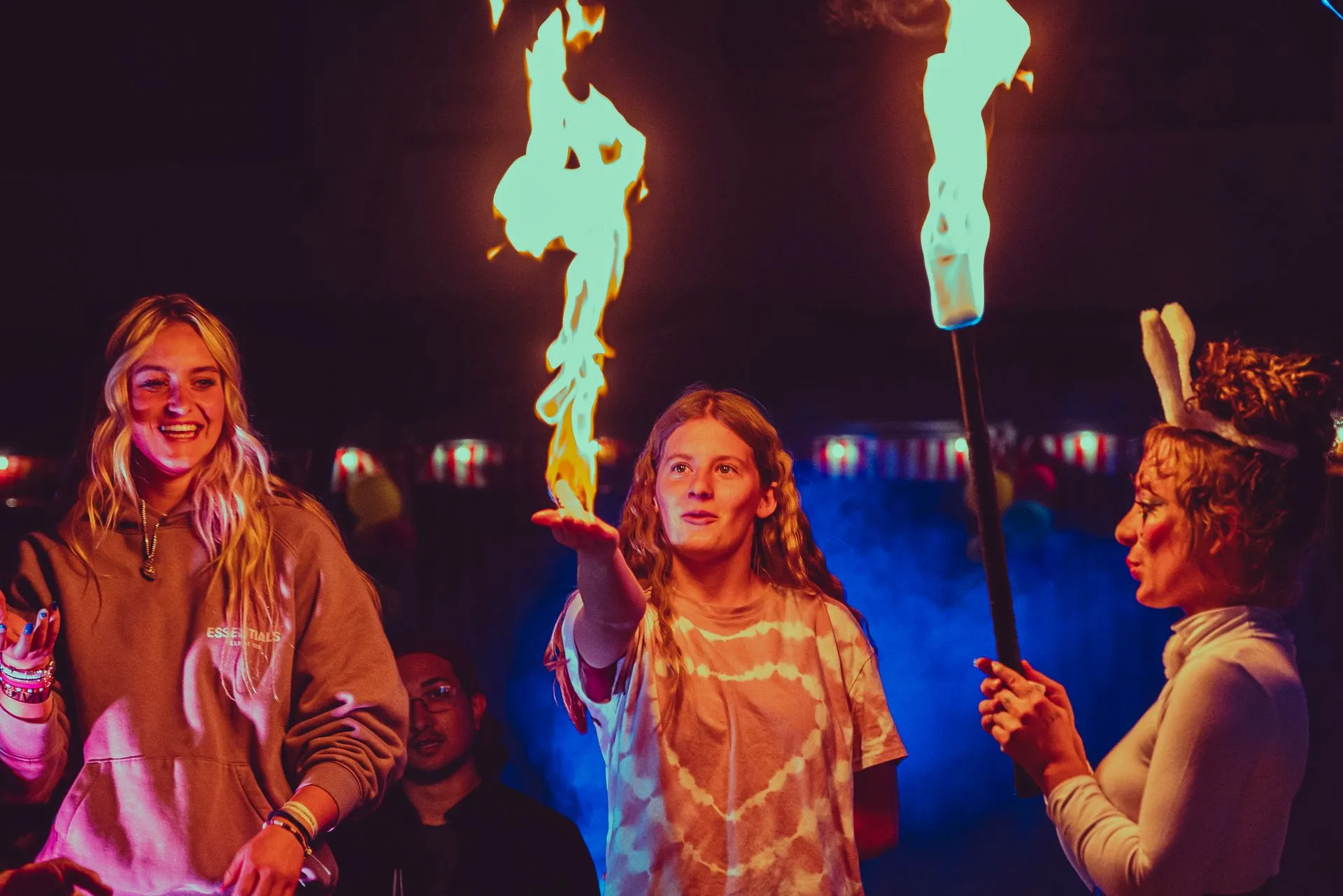 A group of people are standing in front of a fire.