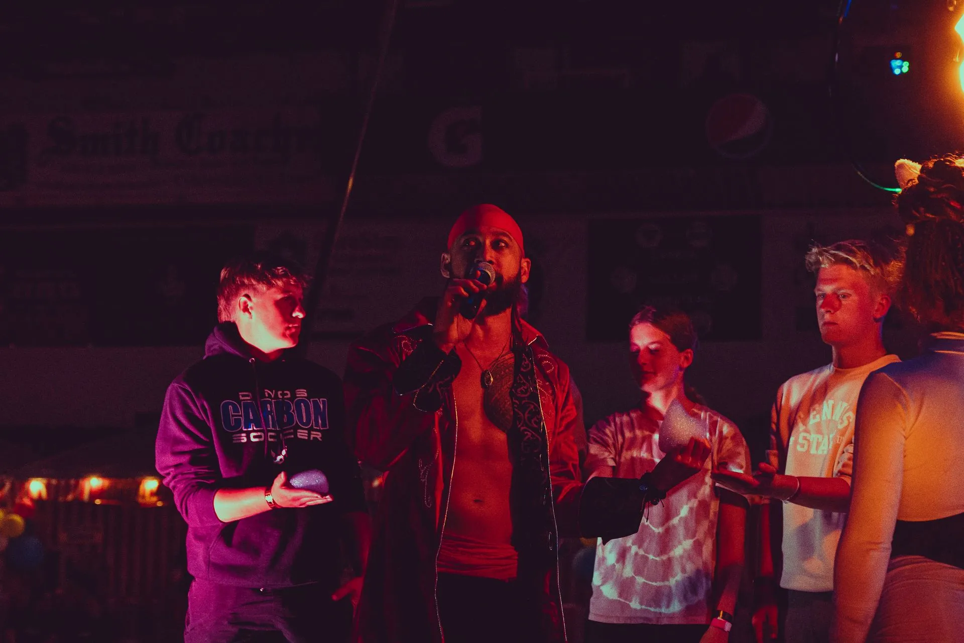 A group of people are standing around a man singing into a microphone.