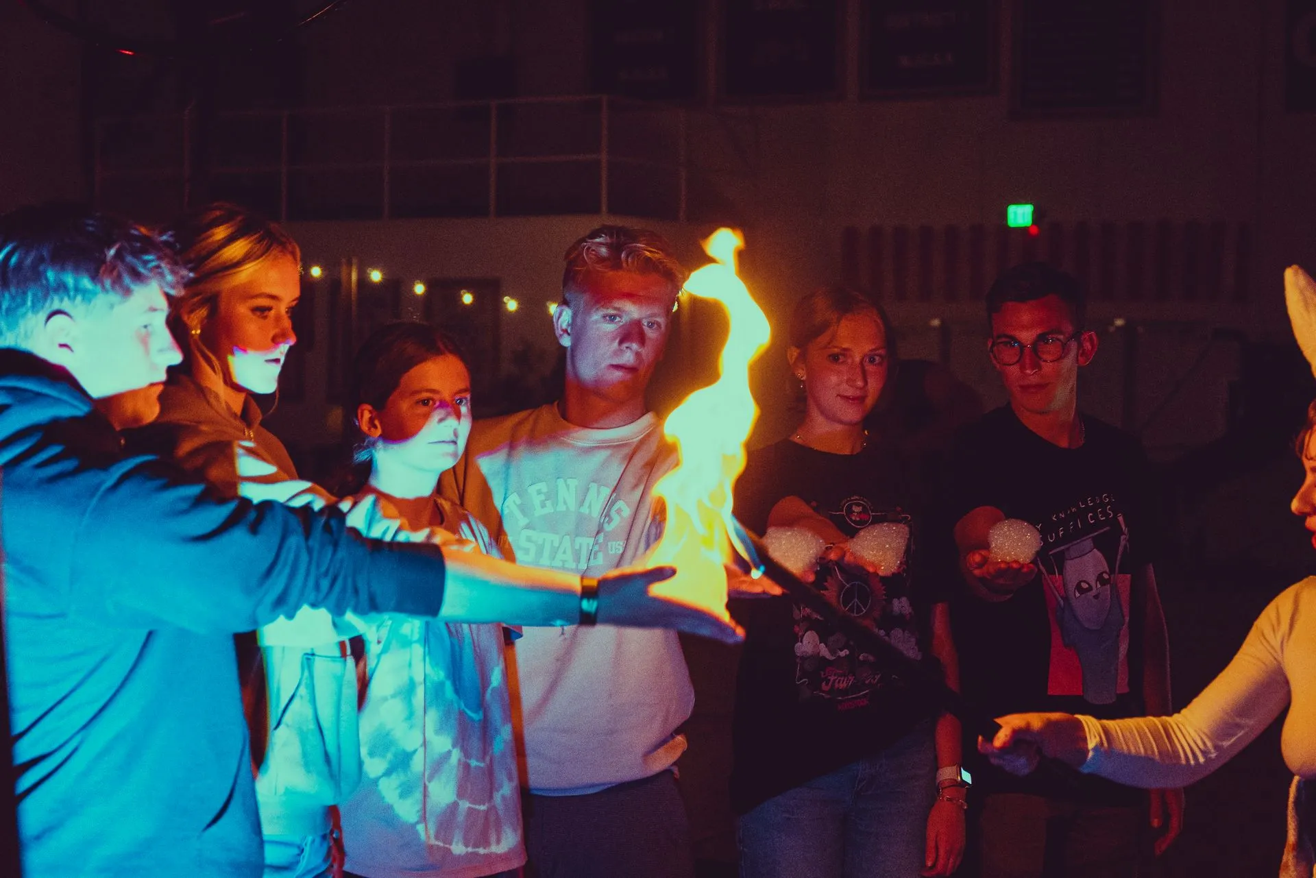 A group of people are standing around a fire.
