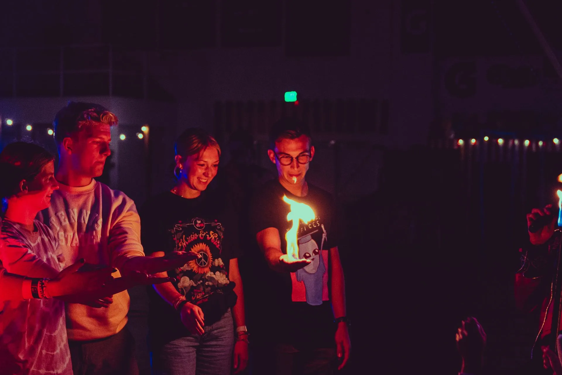 A group of people are standing around a candle in the dark.