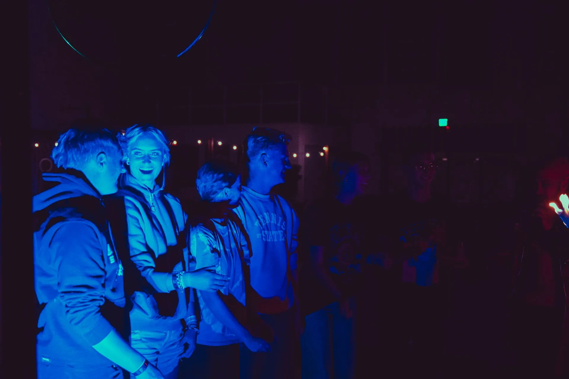 A group of people are standing in a dark room with blue lights.