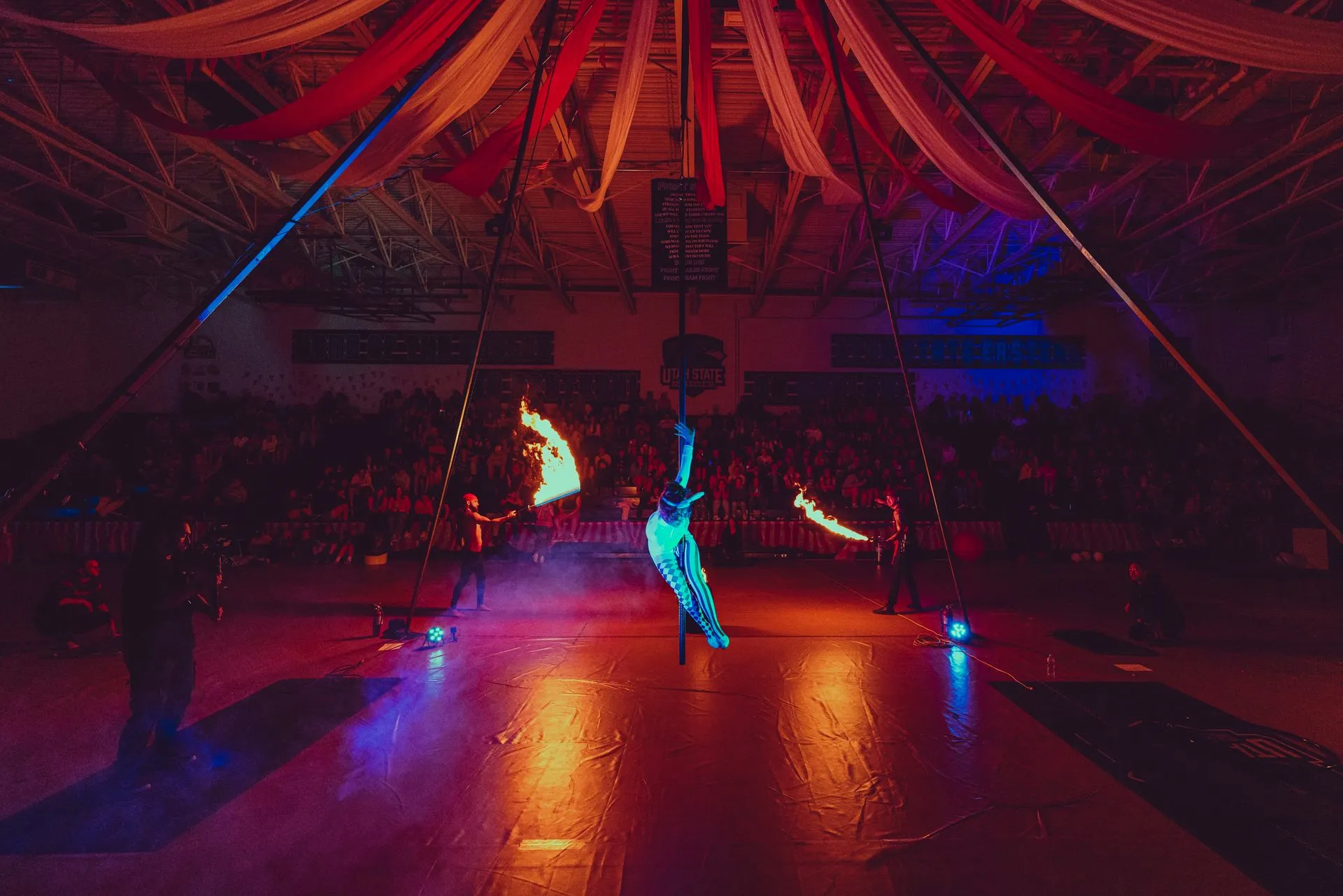 A group of people are performing aerial acrobatics in a gym.