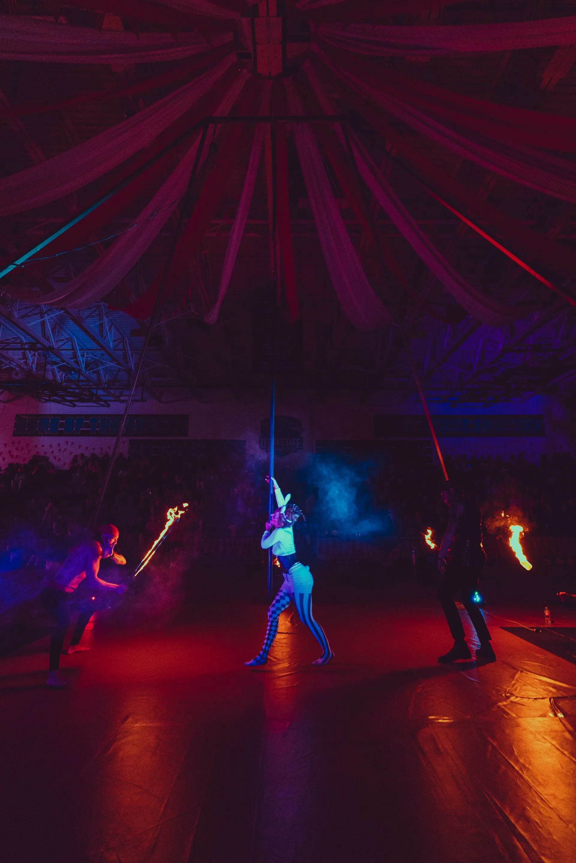 A group of people are performing a fire show in a dark room.
