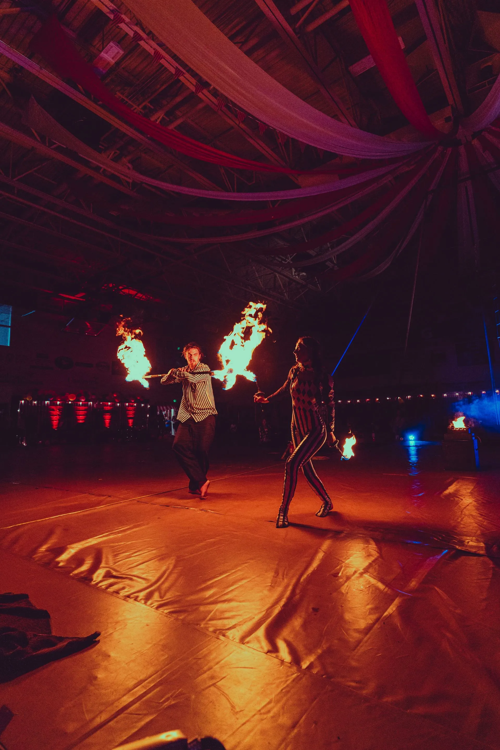A couple of people are dancing with fire in a dark room.