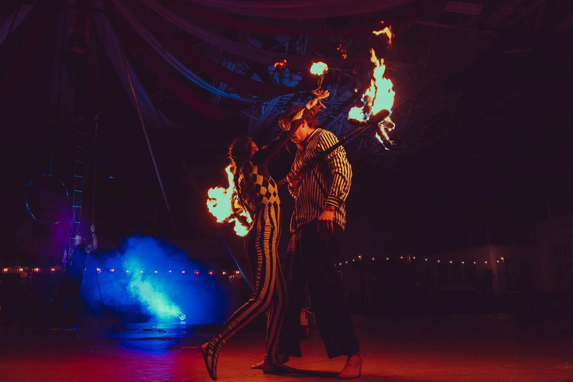 A couple of people are dancing with fire in their hands on a stage.