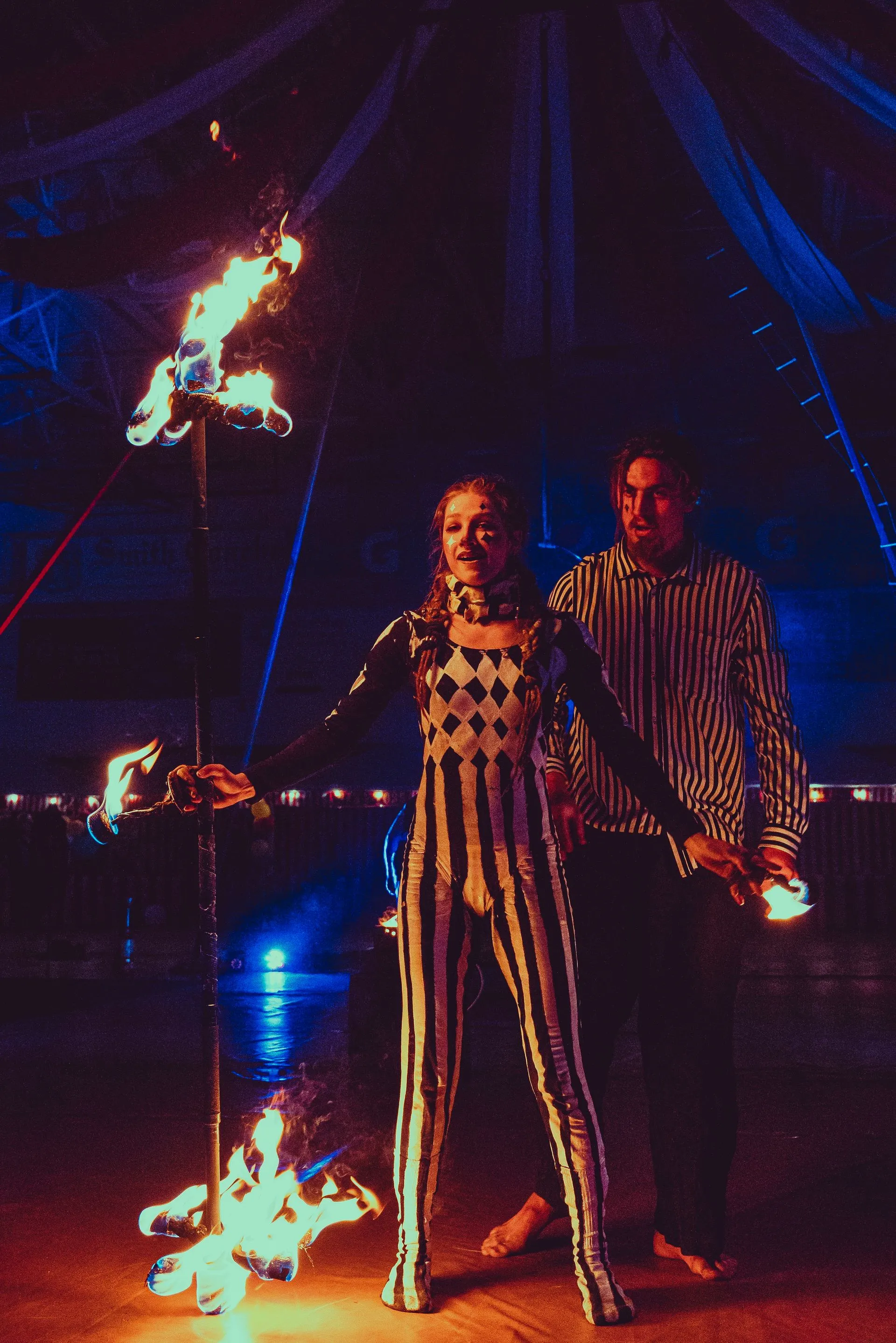 A man and a woman are standing in front of a fire torch.