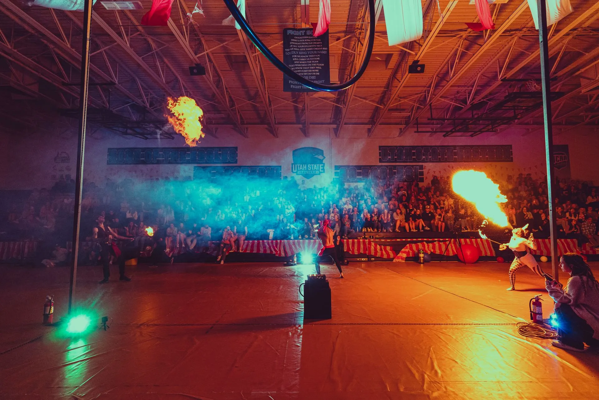 A group of people are performing a fire show in a gym.