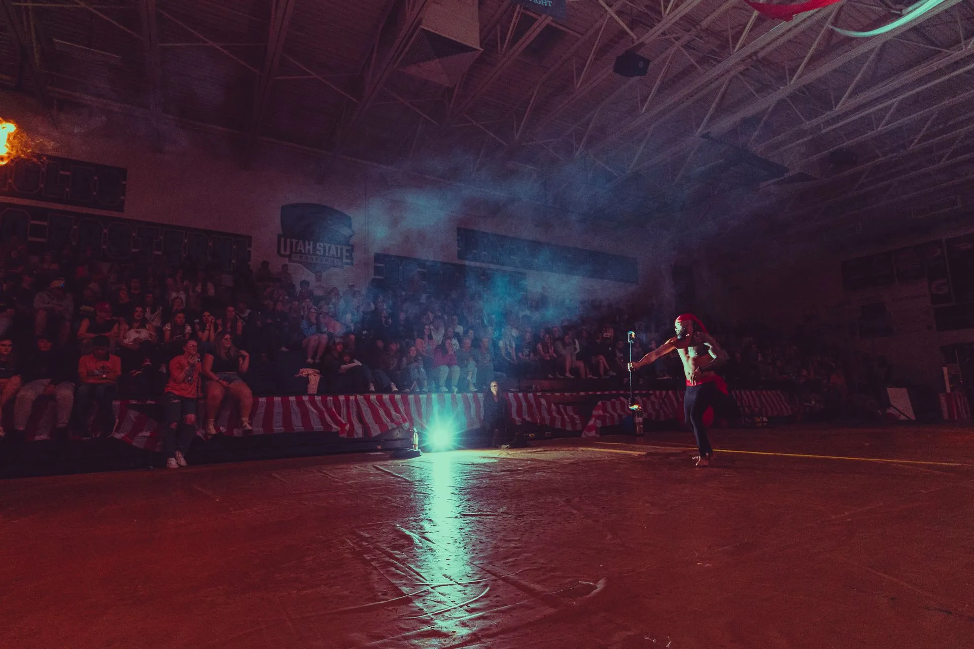 A man is standing on a basketball court in front of a crowd.