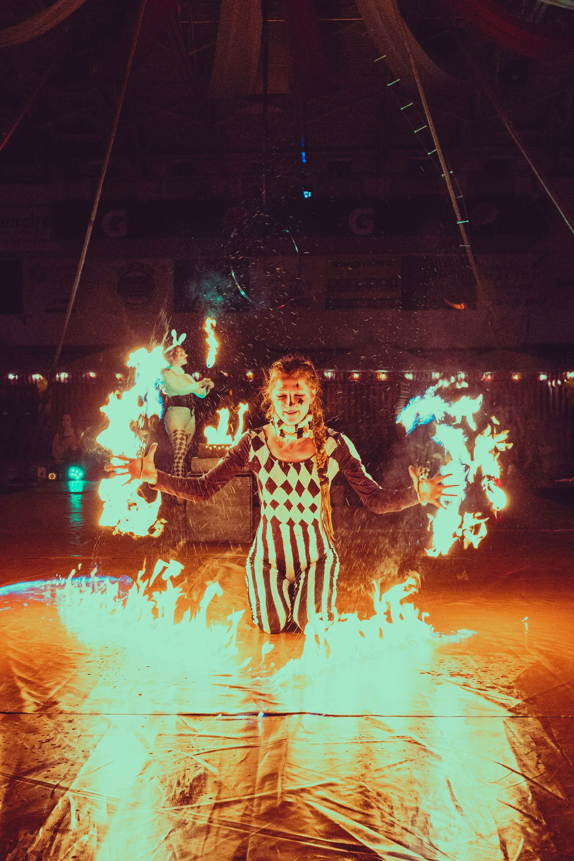 A female performing with Fire Fans with big fire on the ground.