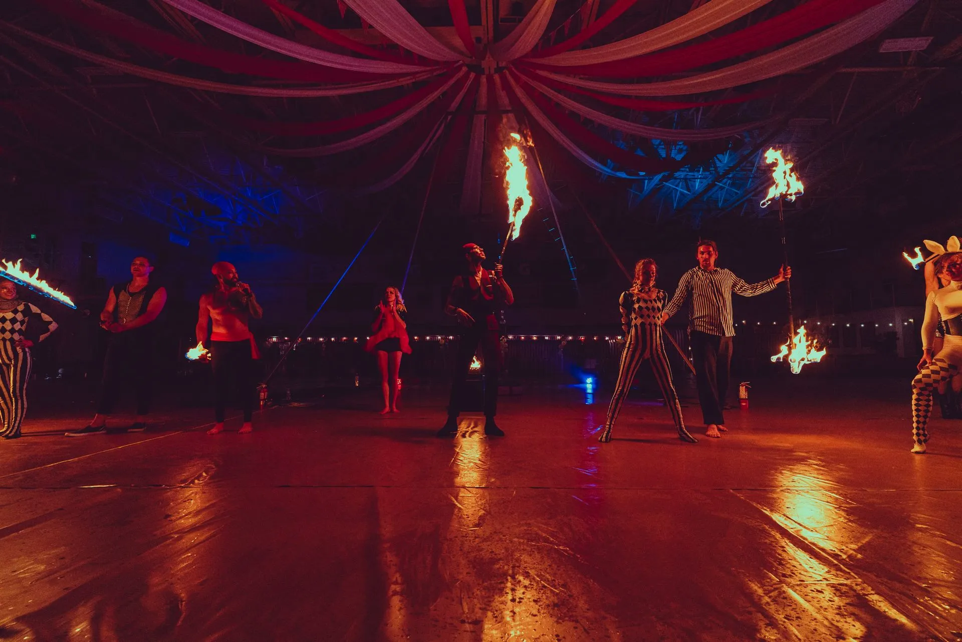 A group of people are dancing with fire in a dark room.