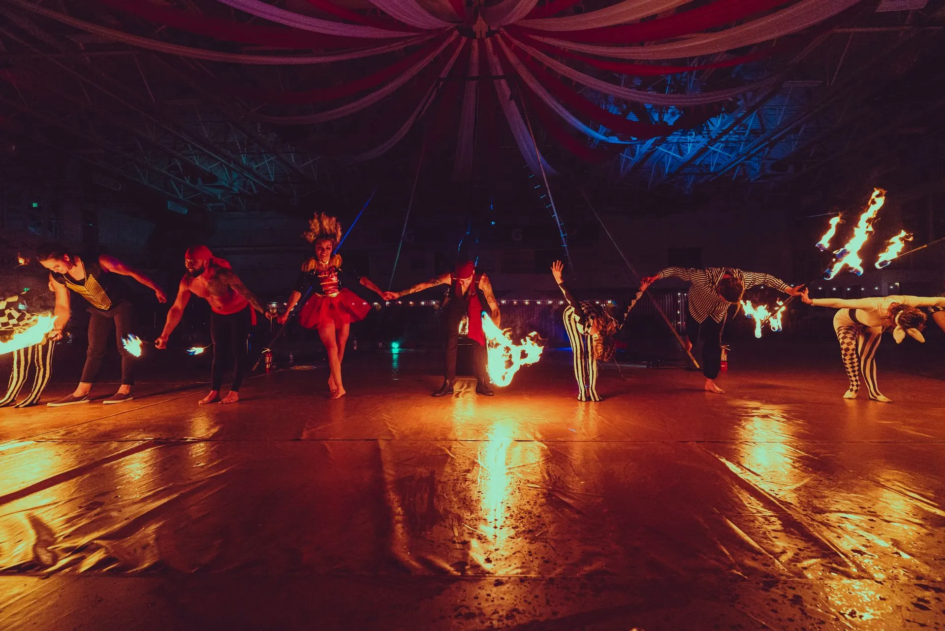 A group of people are dancing with fire in a dark room.