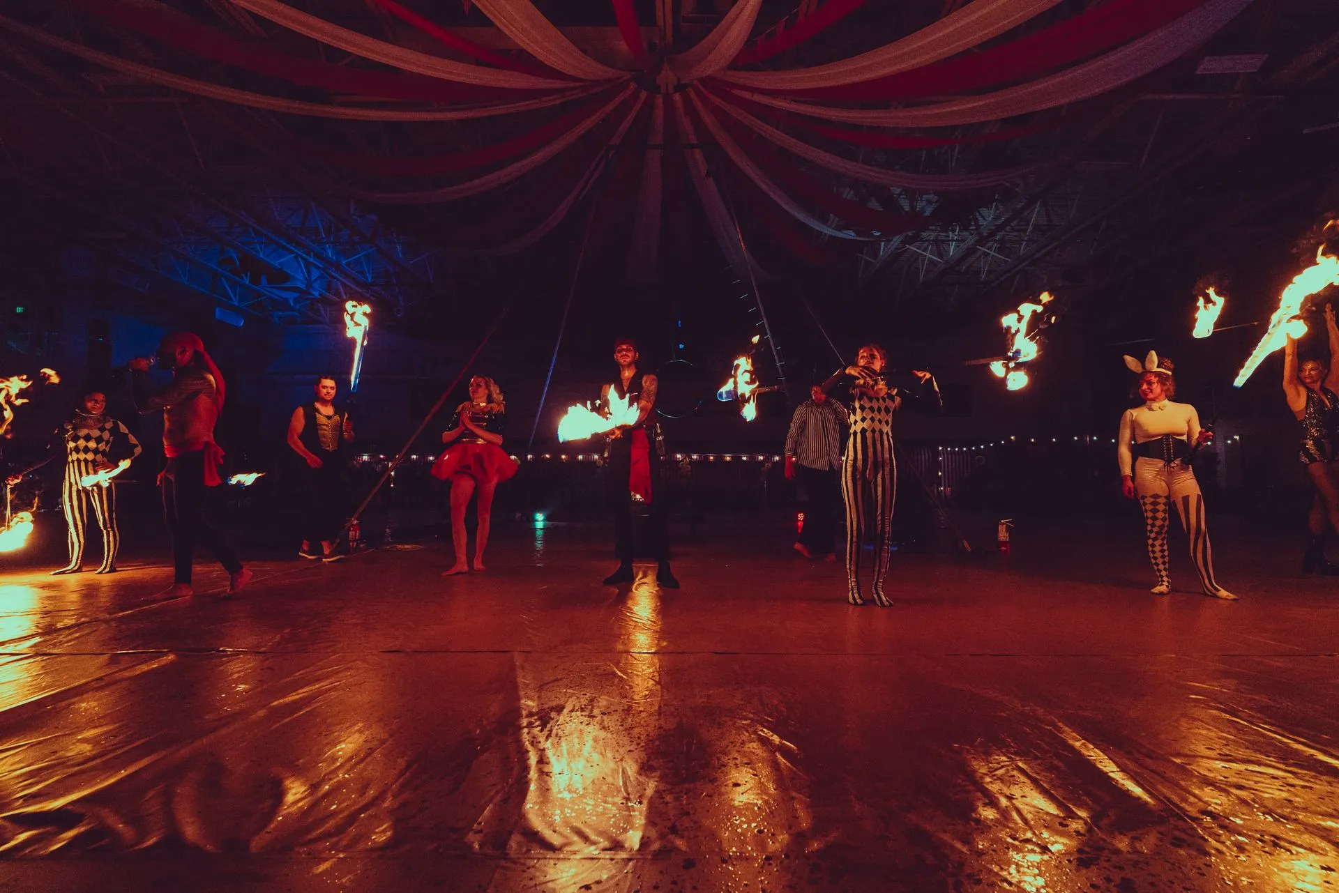 A group of people are dancing with fire in a dark room.