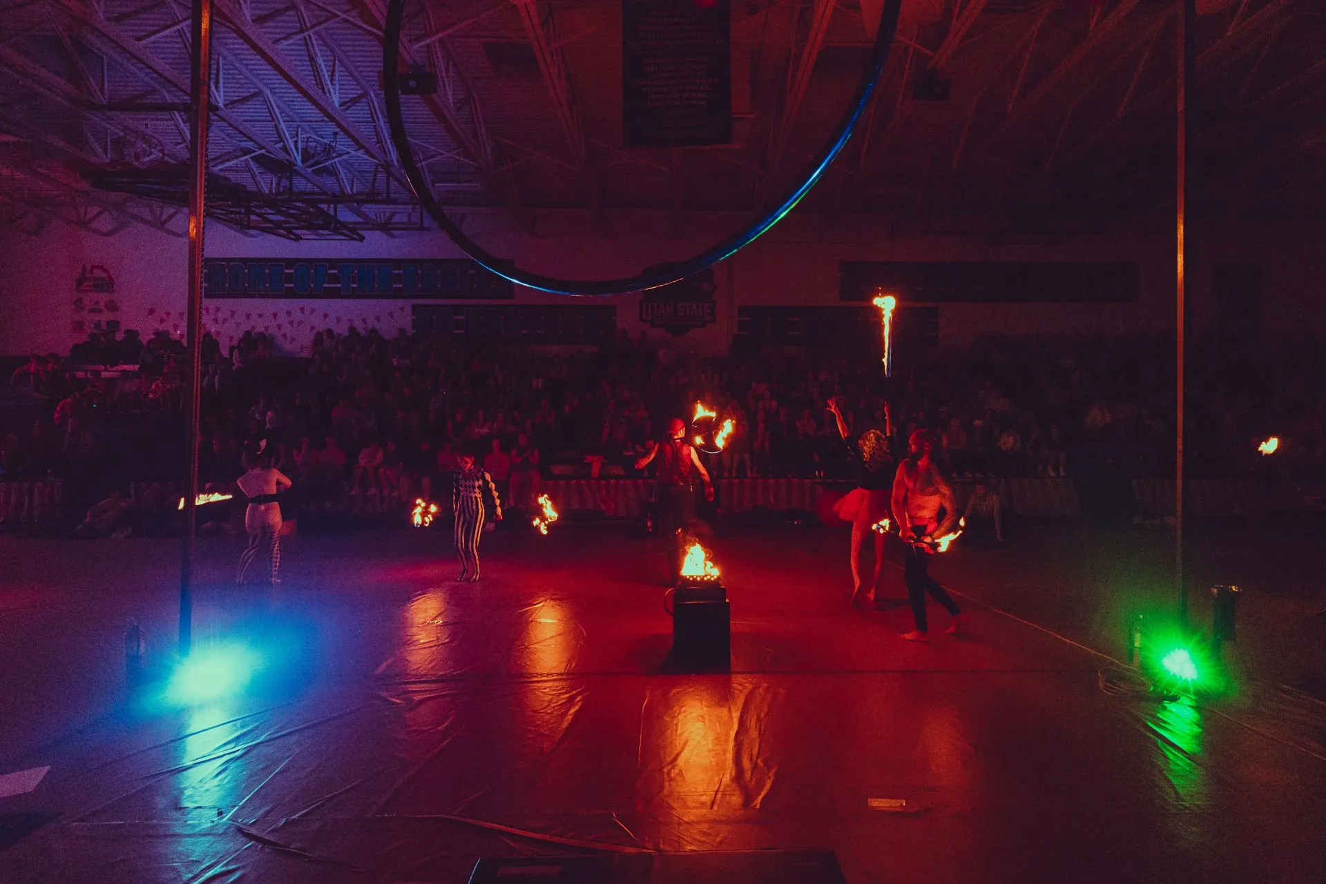 A group of people are performing aerial acrobatics in a gym at night.