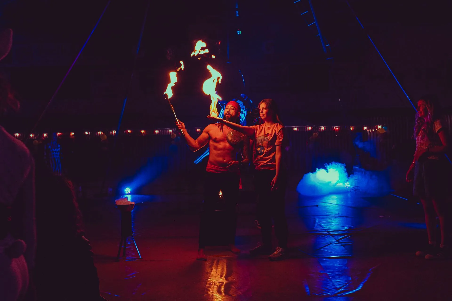 A man and a woman are holding a torch in a dark room.