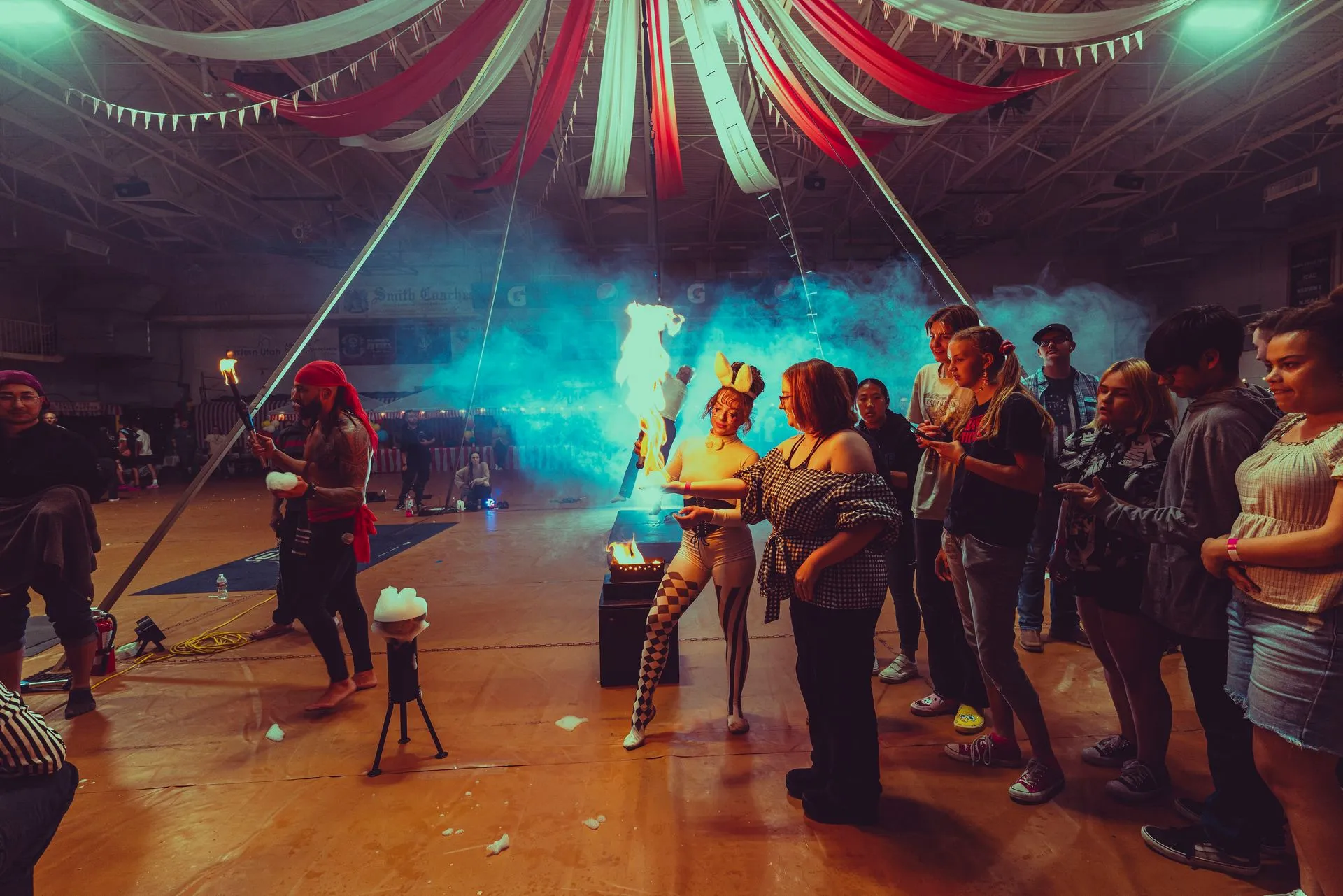 A group of people are dancing in a room with a fire coming out of the ceiling.