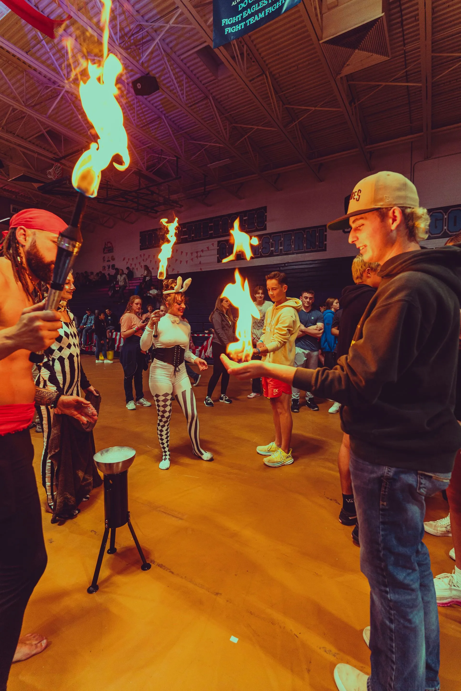 A group of people are standing in a gym holding flaming torches.