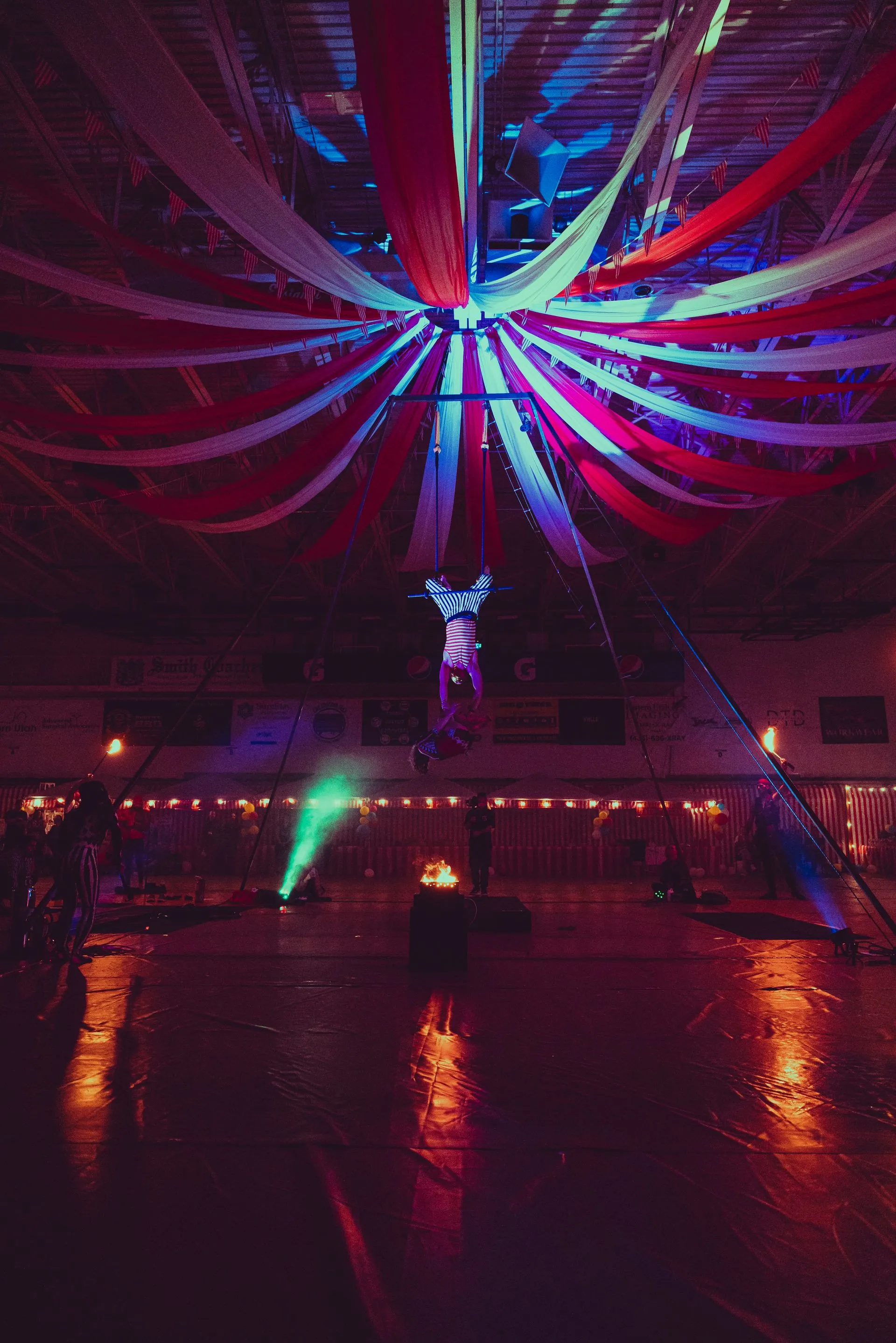 A person is standing in a dark room with a ceiling decorated with red , white and blue ribbons.
