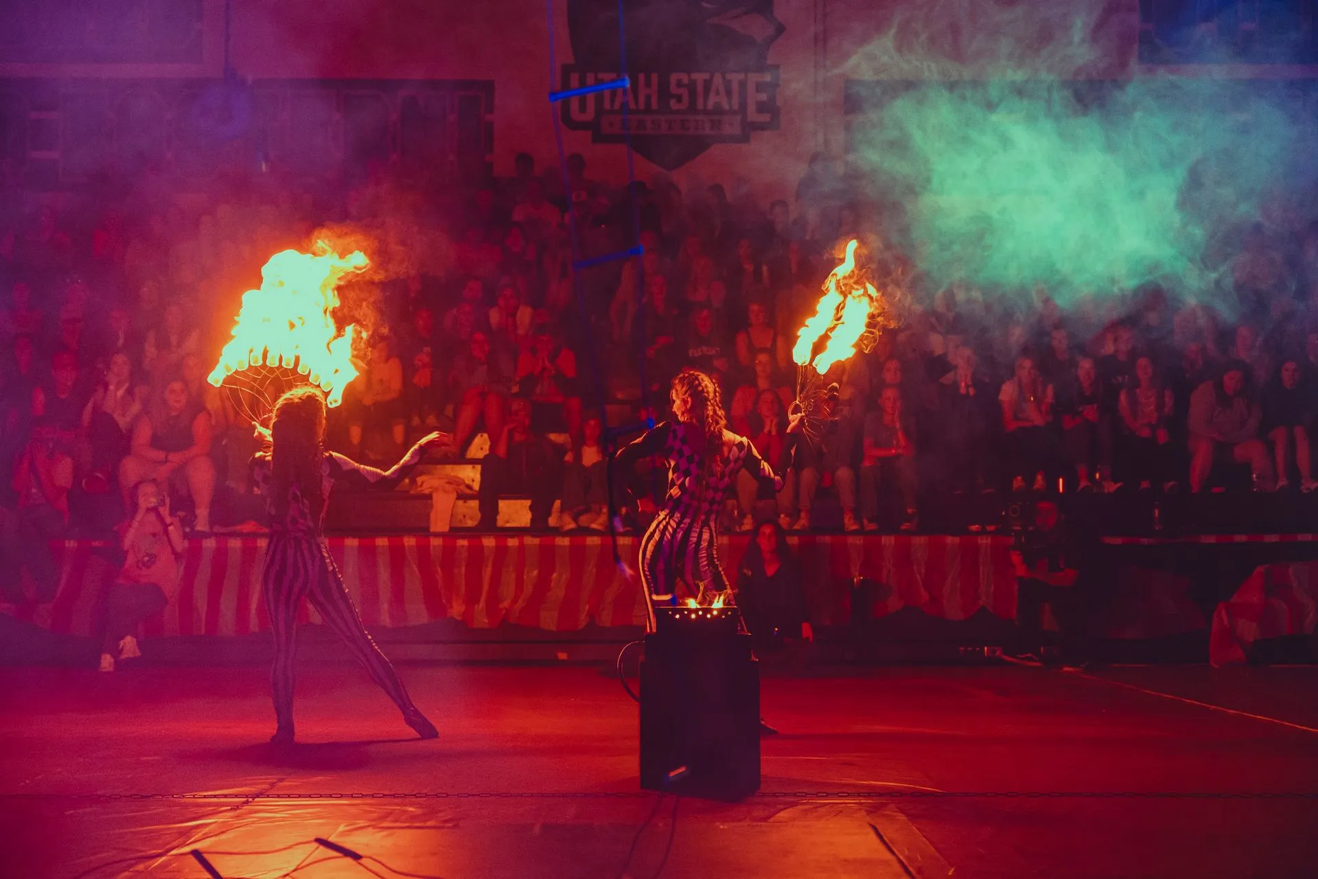 Two women are holding flaming torches in front of a crowd.