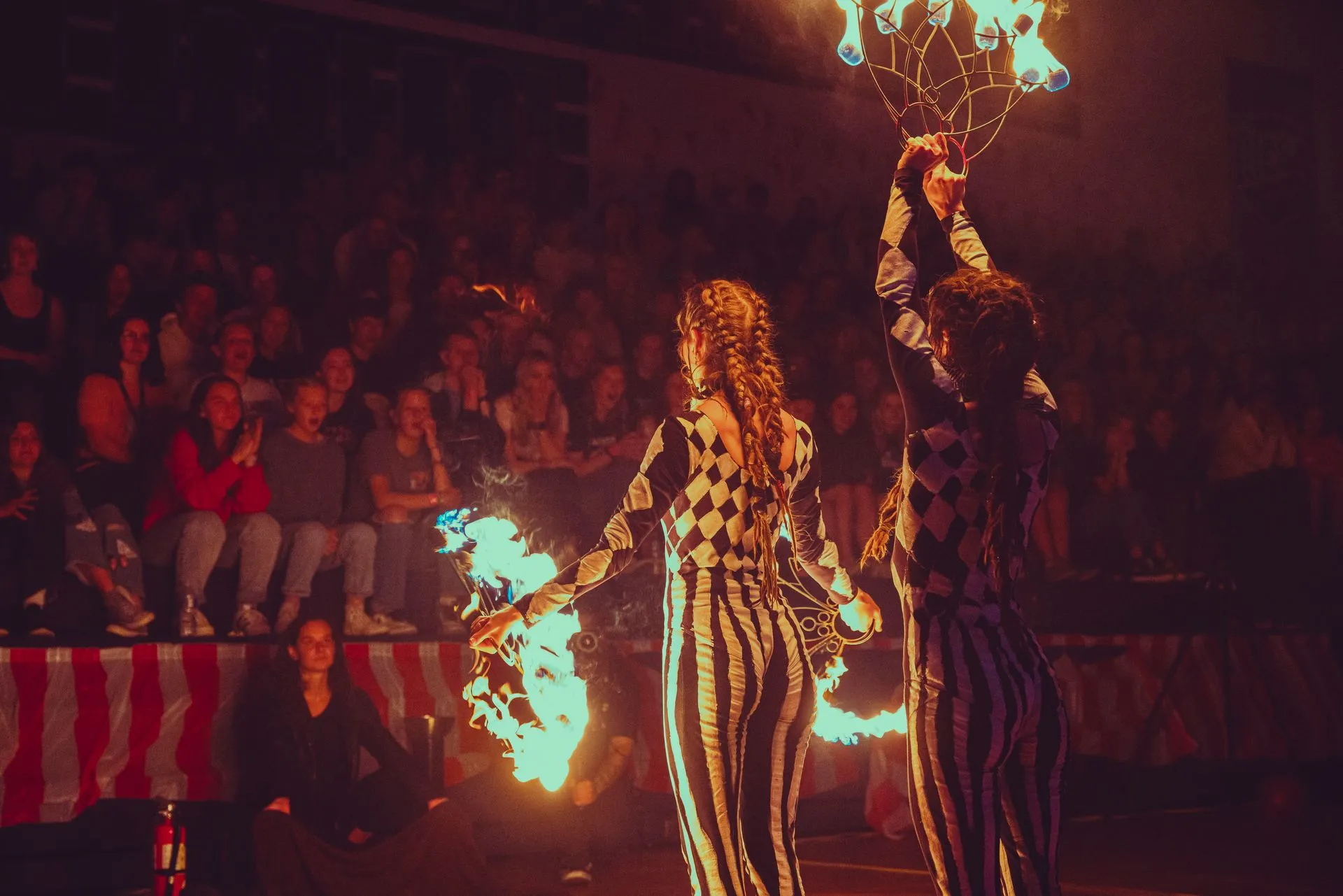 A couple of people are dancing with fire in front of a crowd.