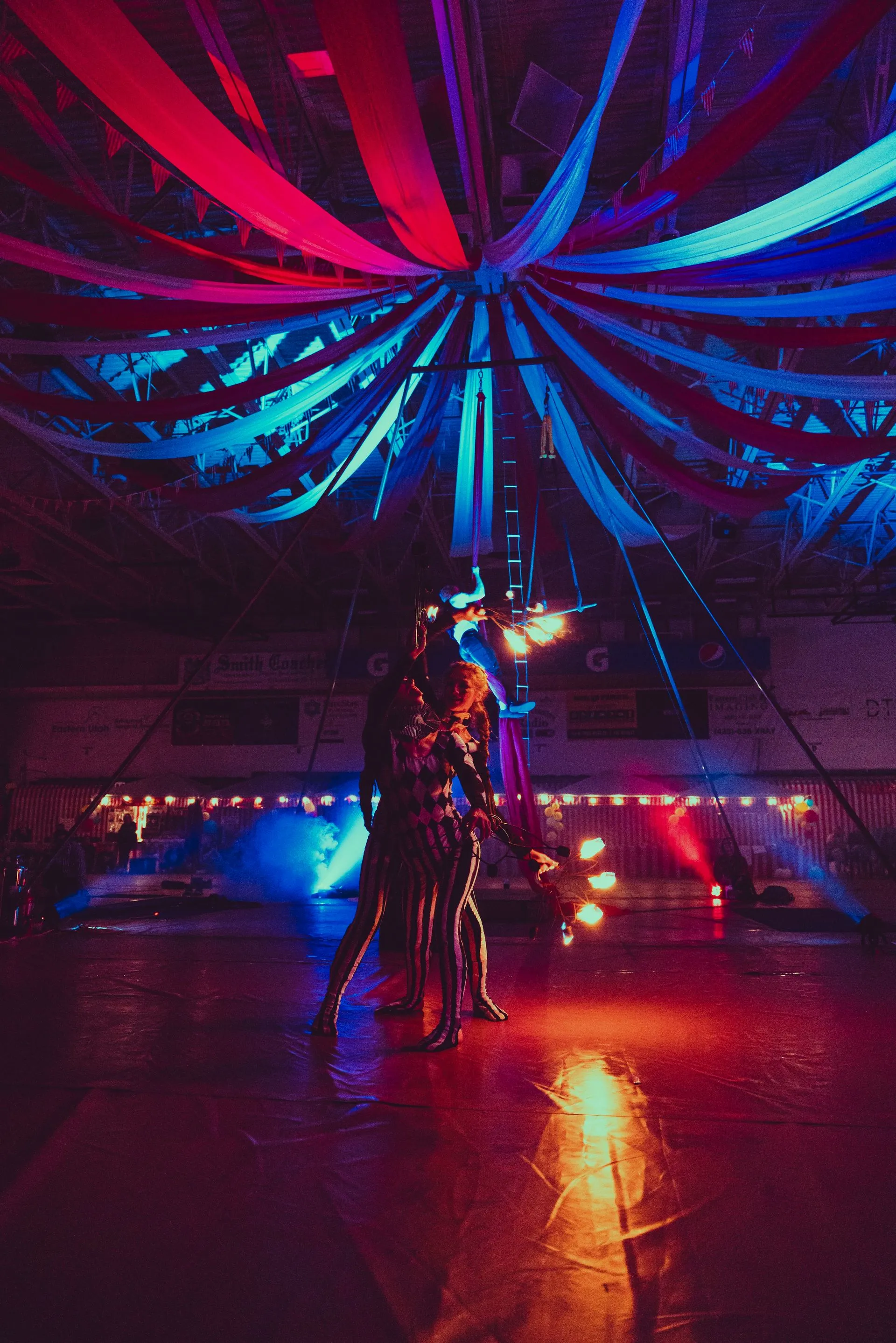 A man and a woman are dancing in a dark room with colorful lights.