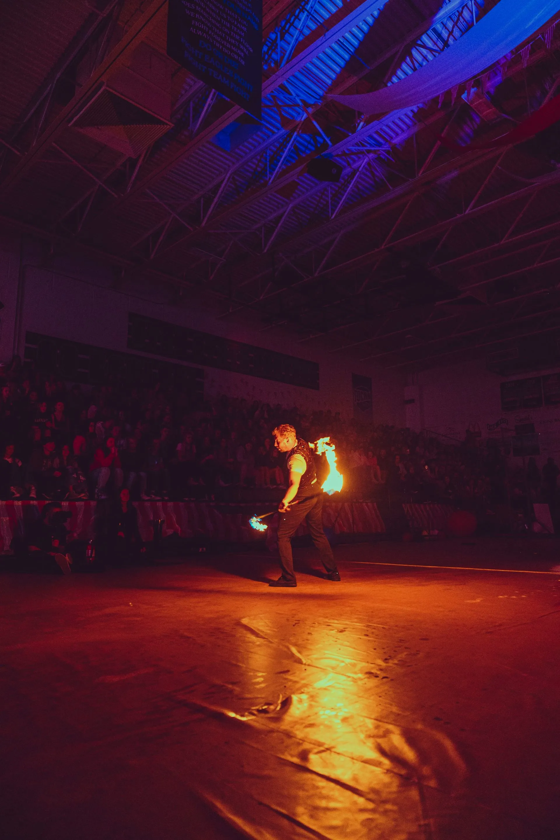 A man is holding a stick of fire in a dark room.