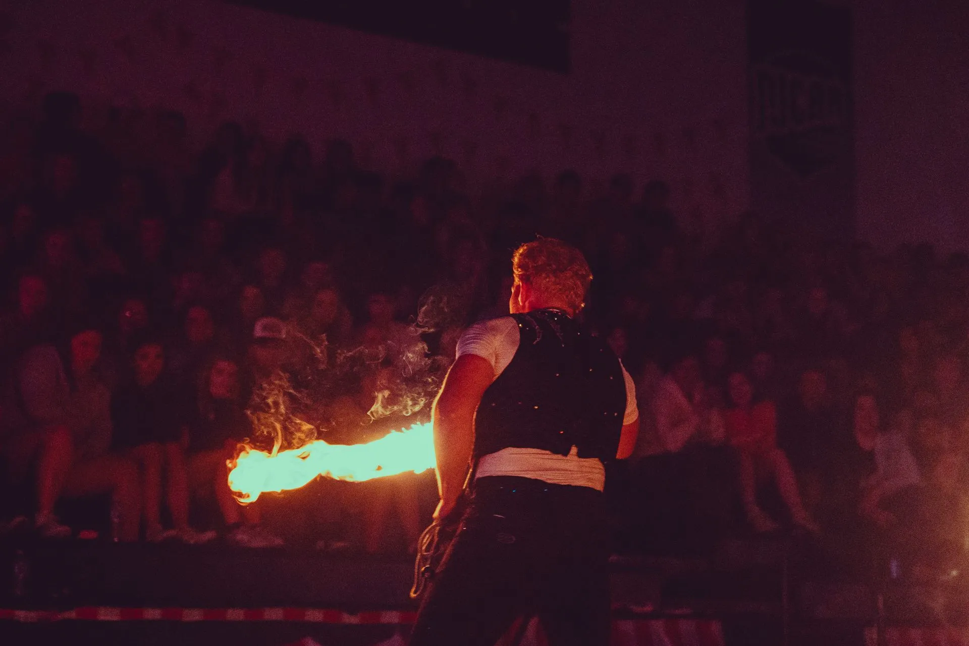 A man is holding a fire torch in front of a crowd.