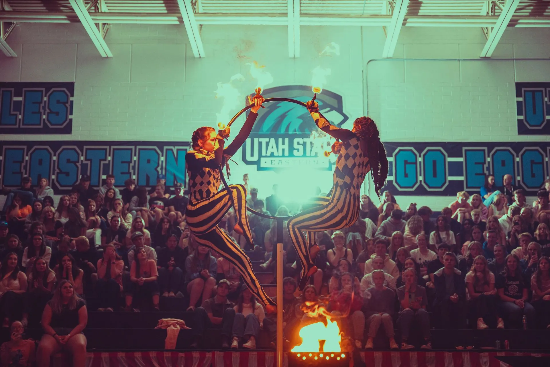 Two cheerleaders are performing in front of a crowd in a gym.